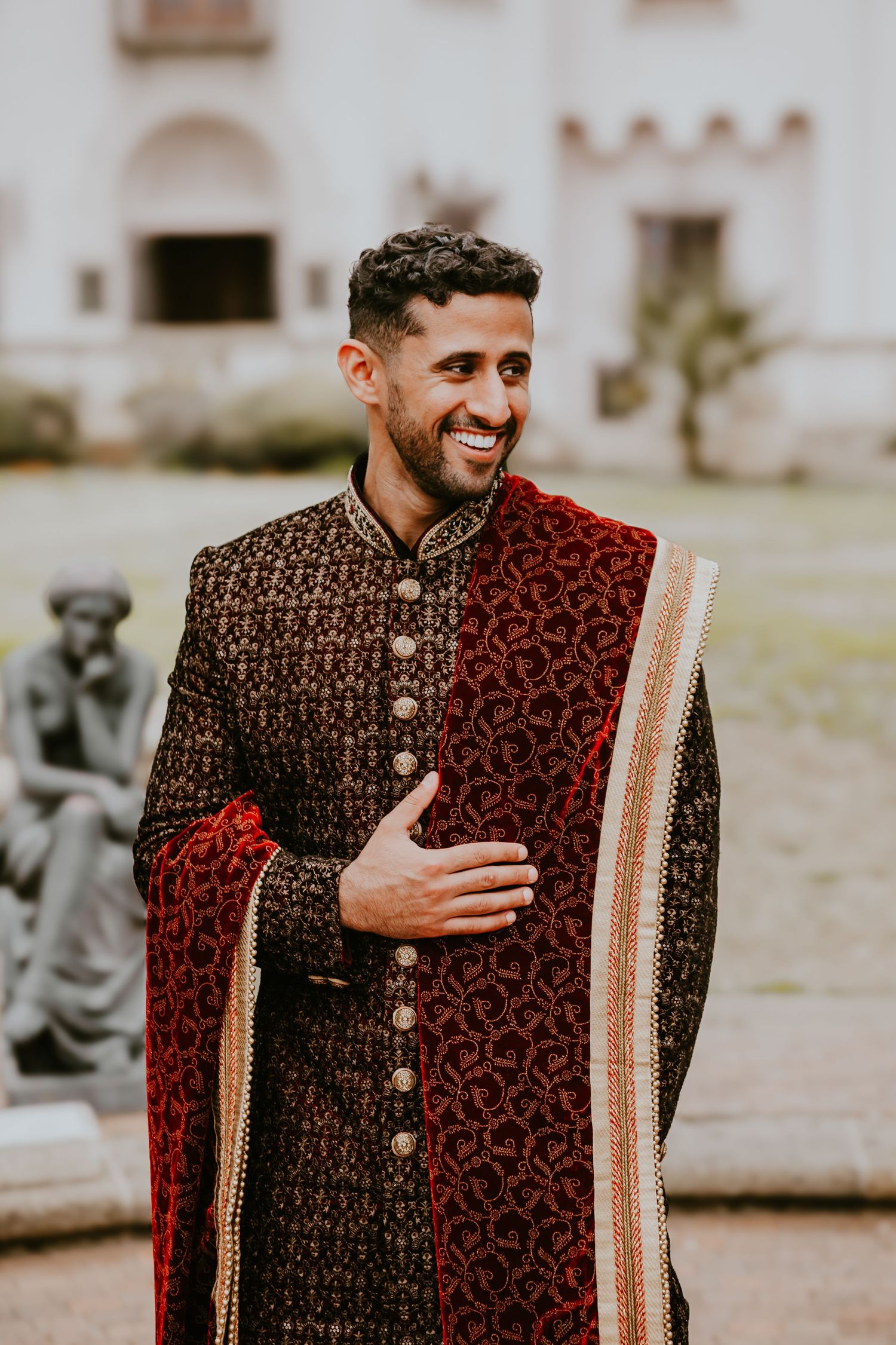 Traditional South Asian groom wearing an elegant brown and red sherwani with detailed embroidery and gold accents.