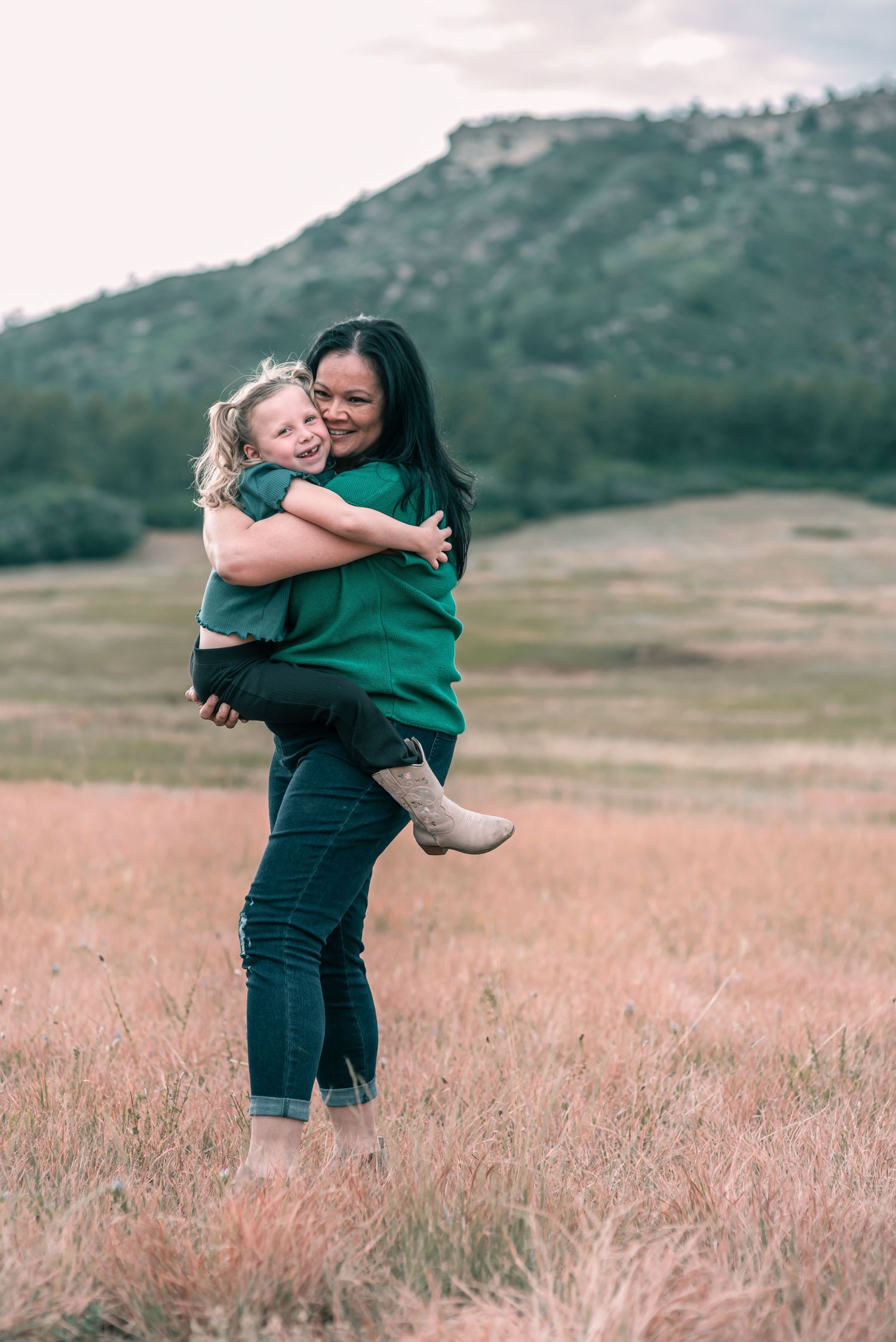 young girl being held and hugged by a woman in a field