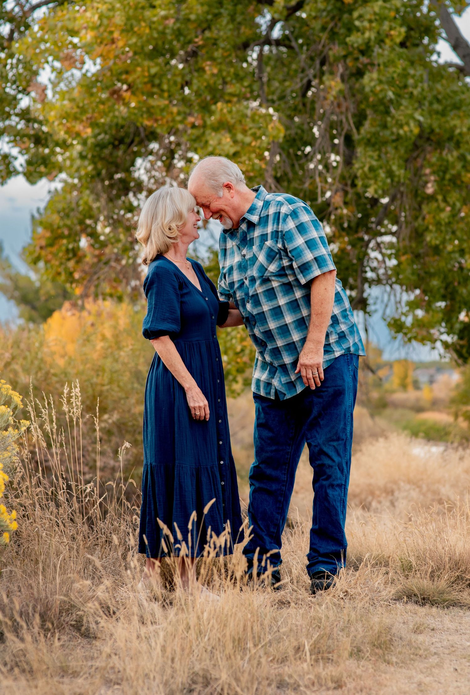couple in love wearing blue outfits in front of a cottonwood tree