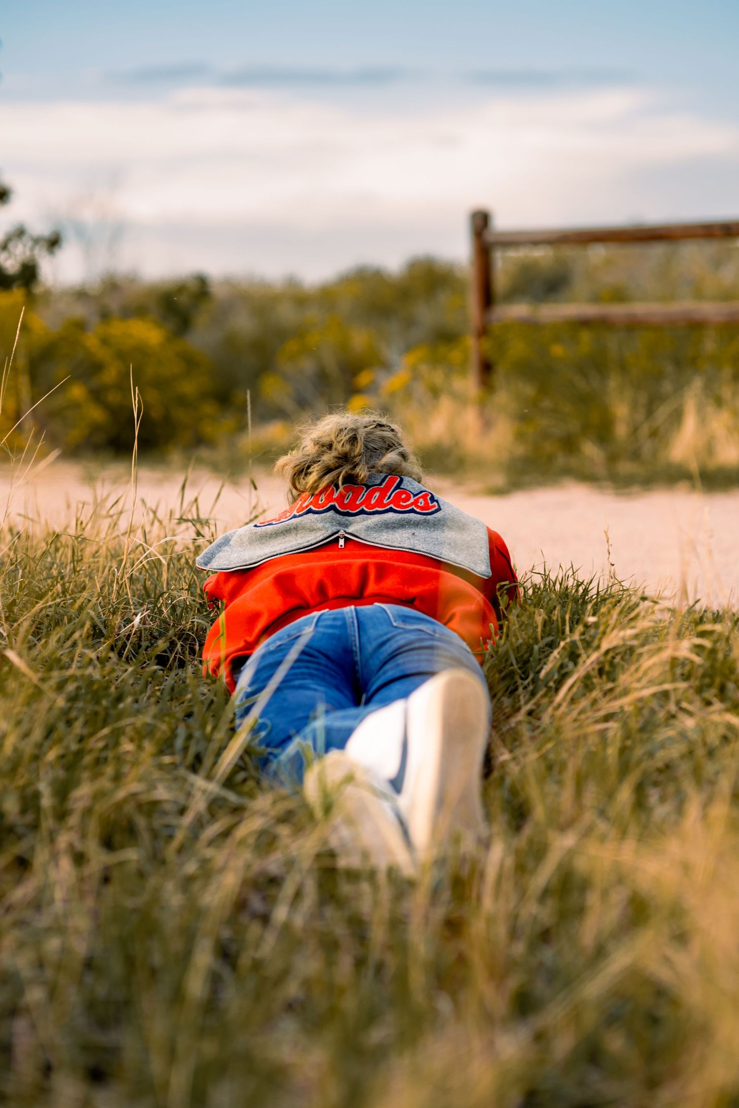 young woman laying in the grass wearing a letterman jacket