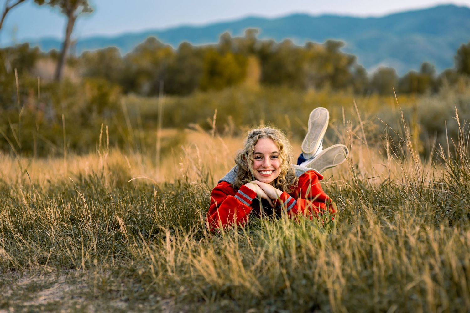Young lady laying in the grass at Chatfield State Park, posing for senior photos.