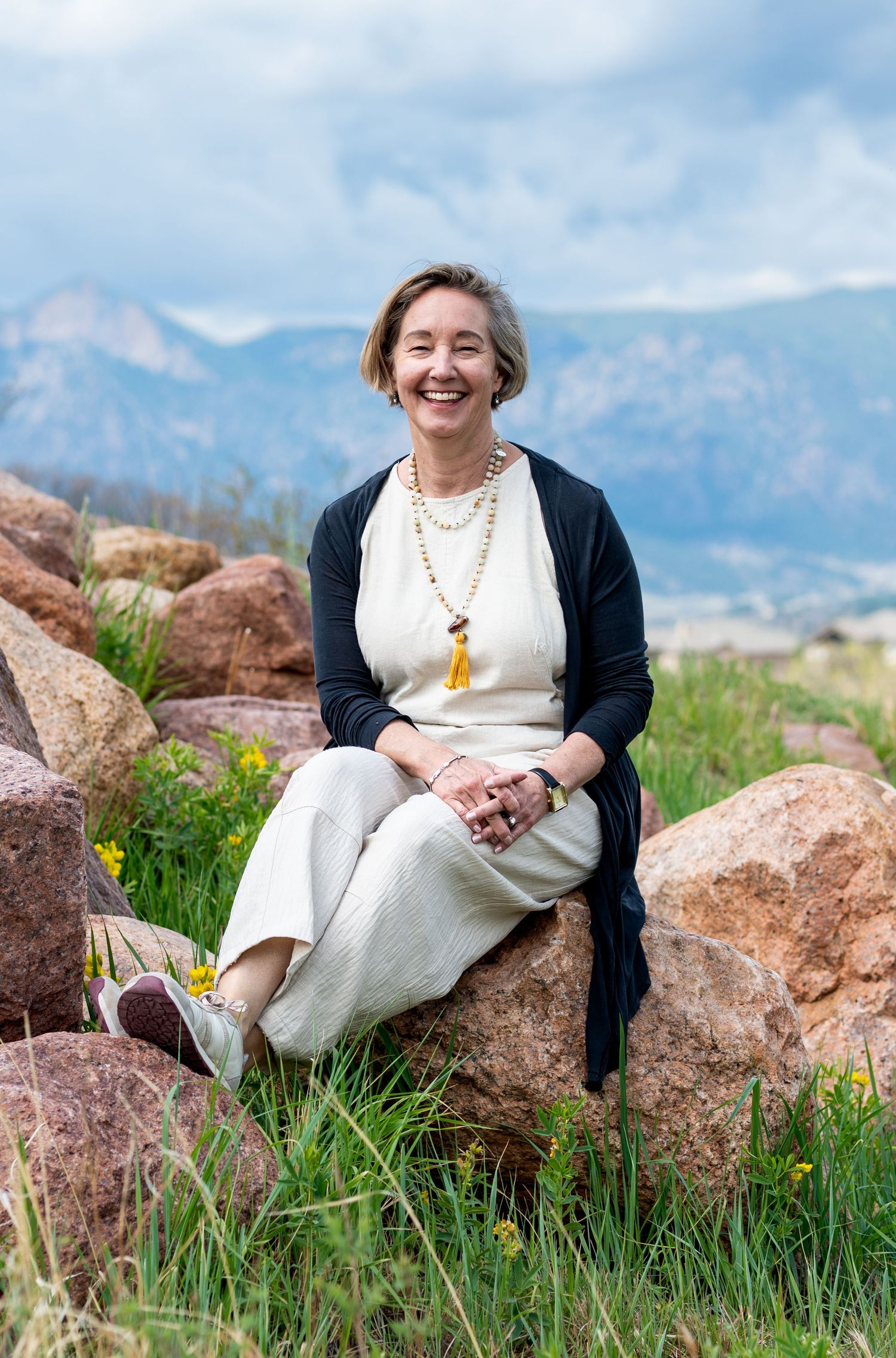 Woman in the sunshine sitting on a rock with Pikes Peak in the background