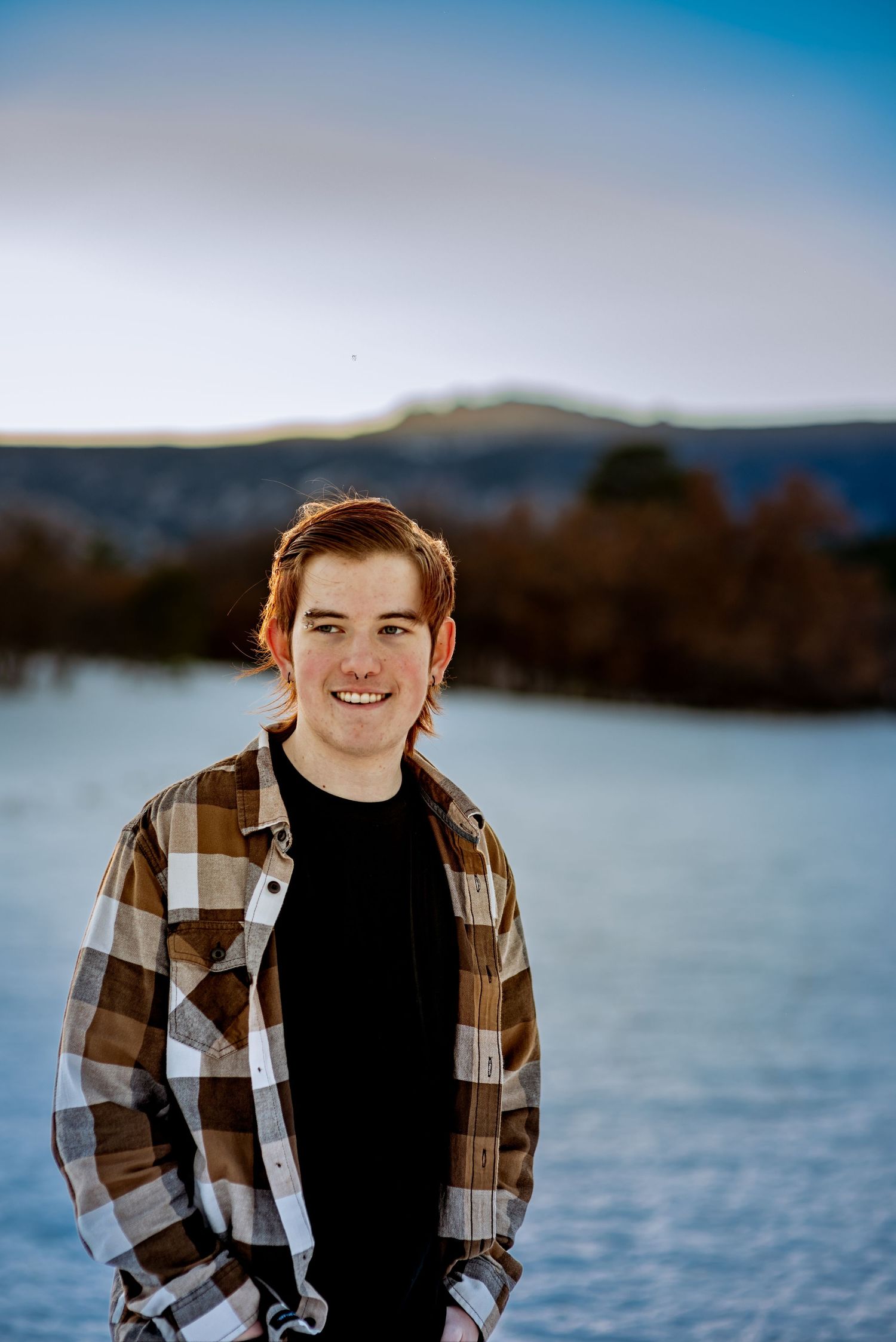senior photo of a young man with a snowy background as the sun is setting