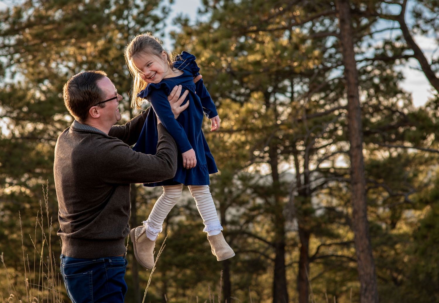 Dad picking up daughter and lifting her in the air while she giggles