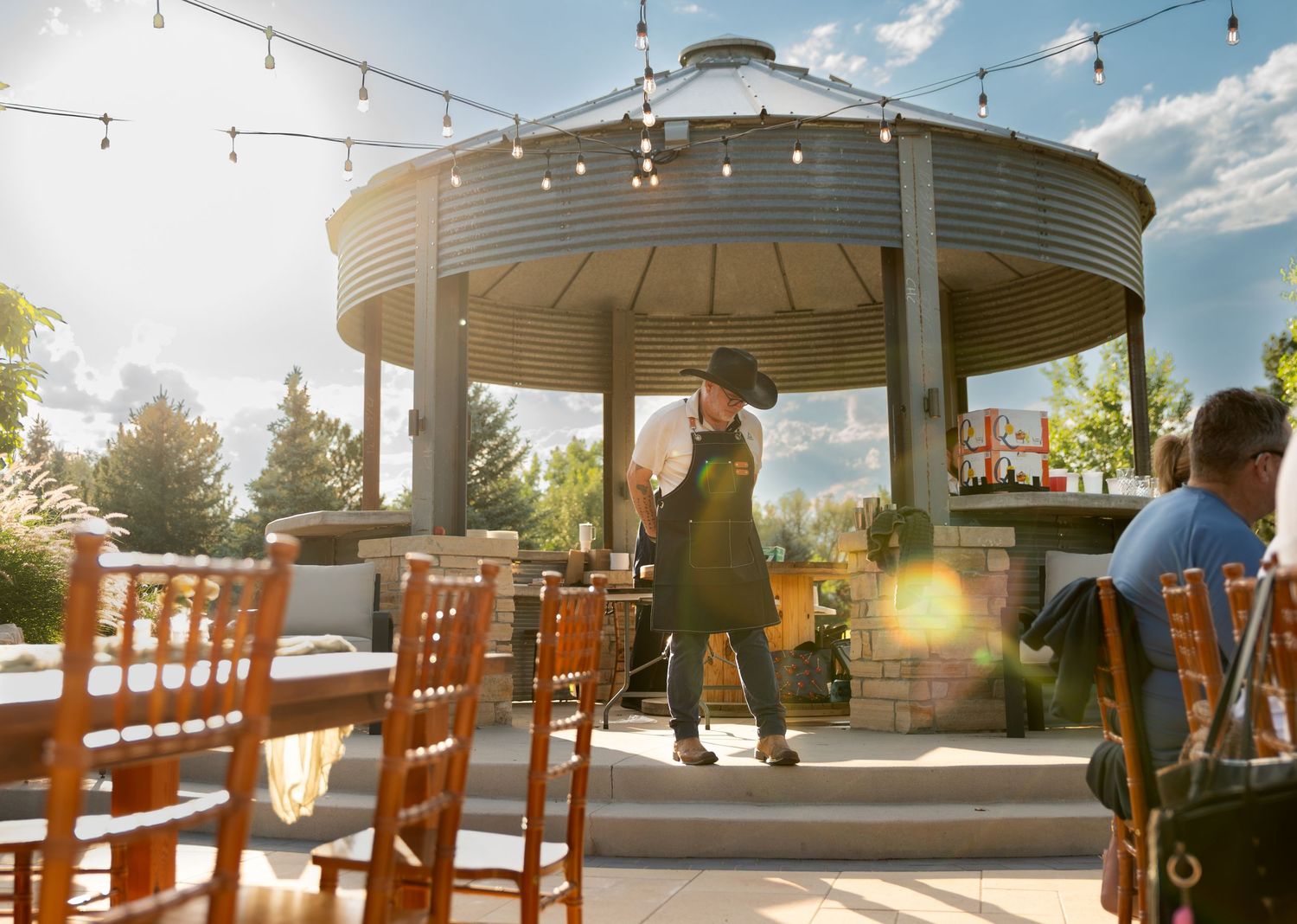 Bartender of Intoxicology mobile mixology talking at an outdoor event with a solar flare at Lazy Stud Ranch in Lyons, CO.