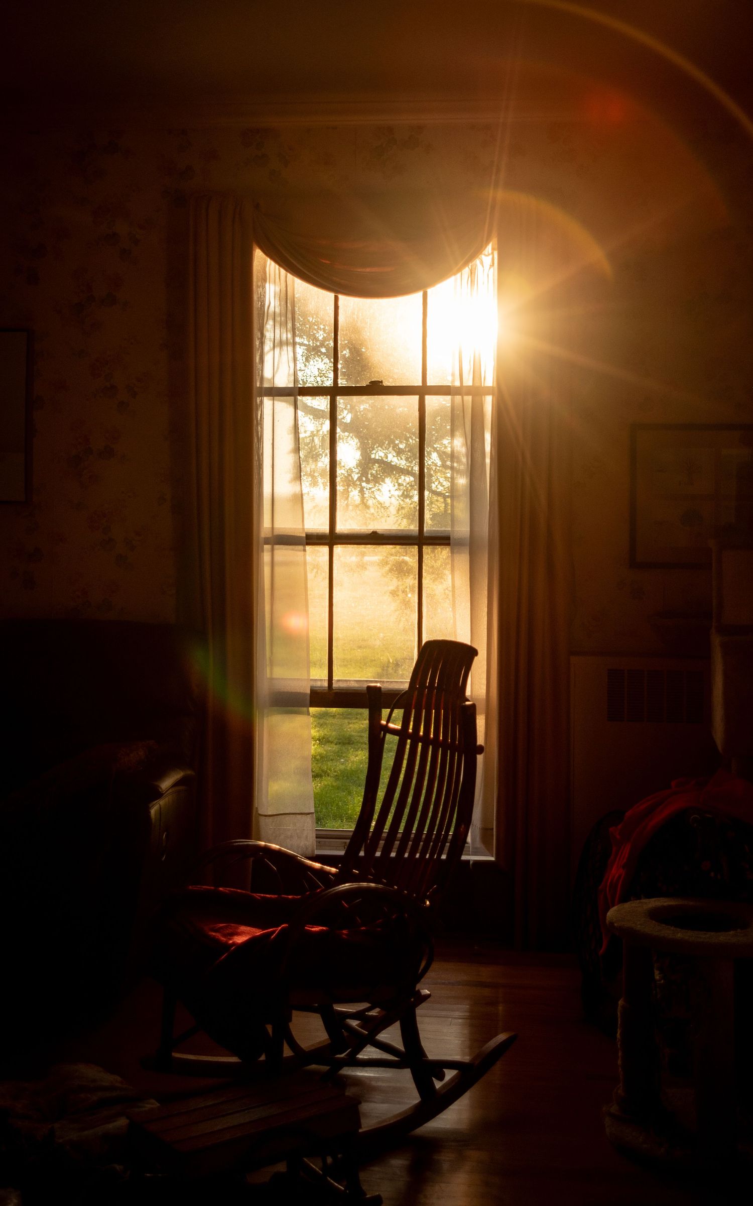 rocking chair silhouette with a solar flare coming through a window with warm light