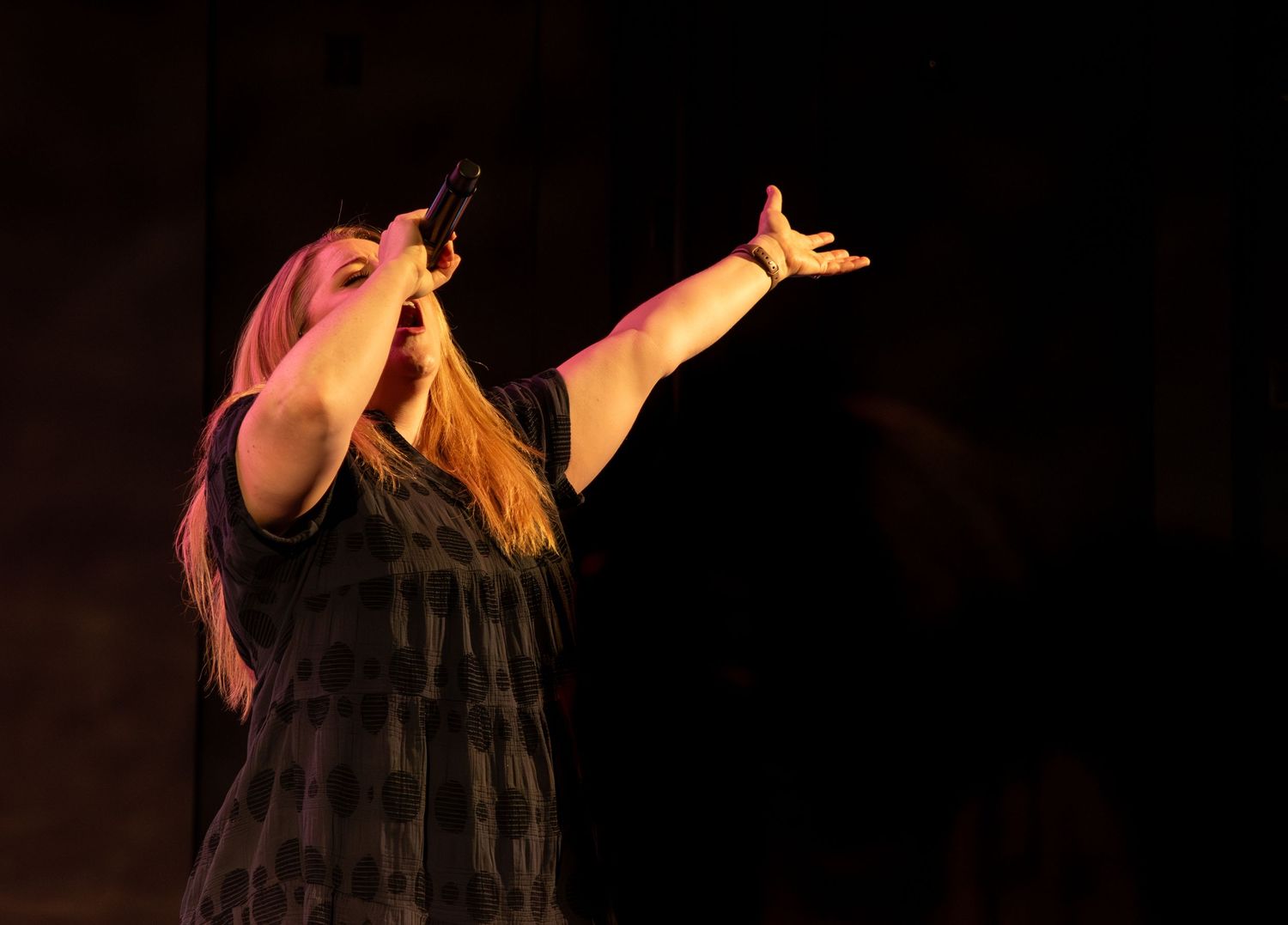 Woman singing into a microphone worshiping at Zeal Church, Colorado Springs. Photo by Elijah Grace Photo