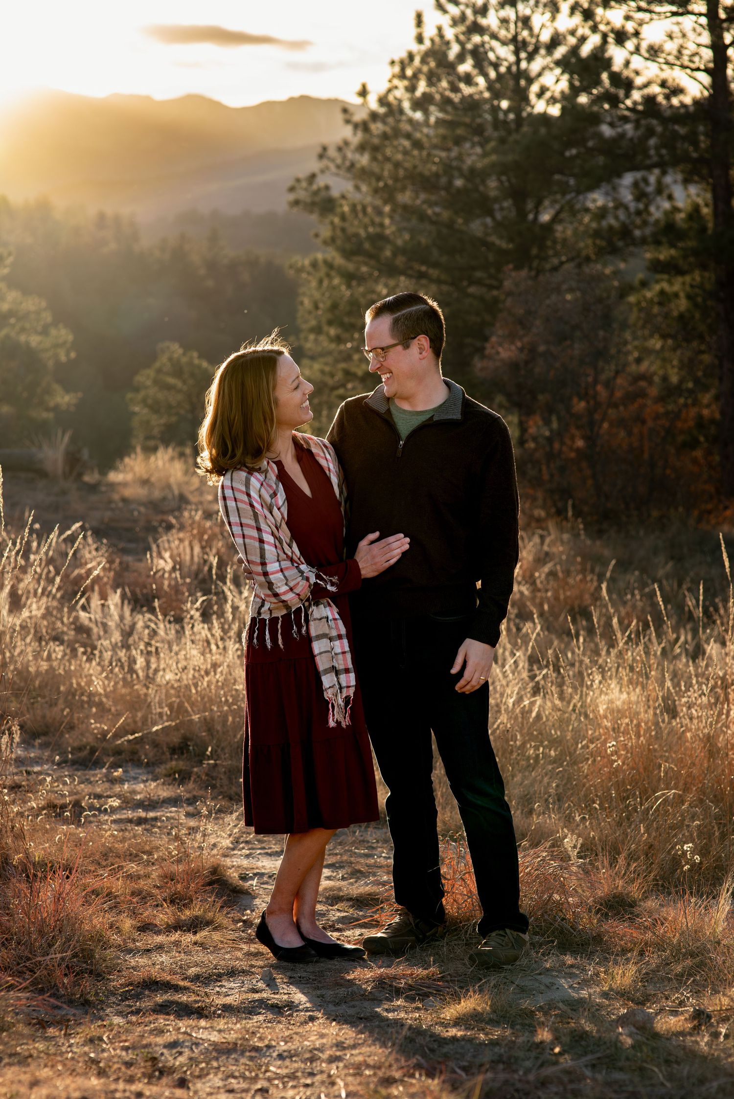 Couple looking at each other lovingly with mountains in the background at Ute Valley, Colorado Springs, CO during golden hour