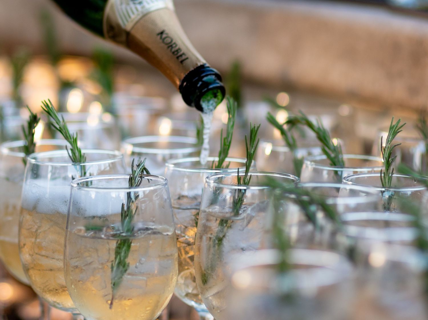 Bubbly drink being poured into a glass with rosemary. Photo by Elijah Grace Photo.