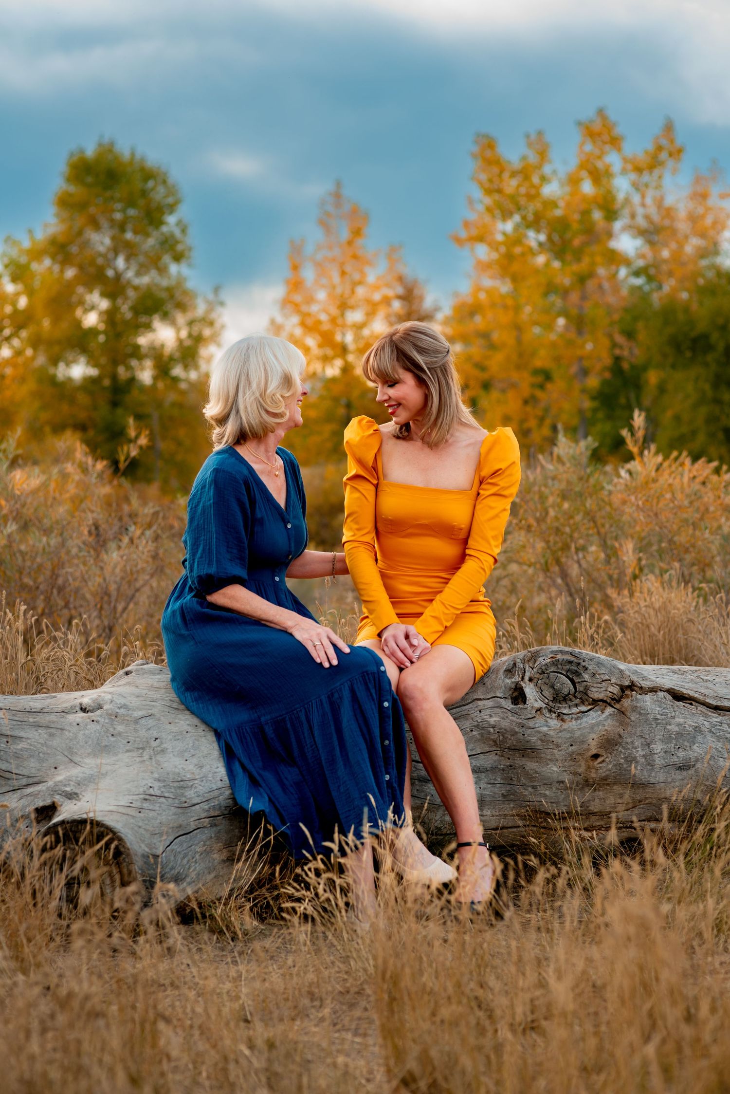Mother and daughter talking while resting on a fallen tree trunk