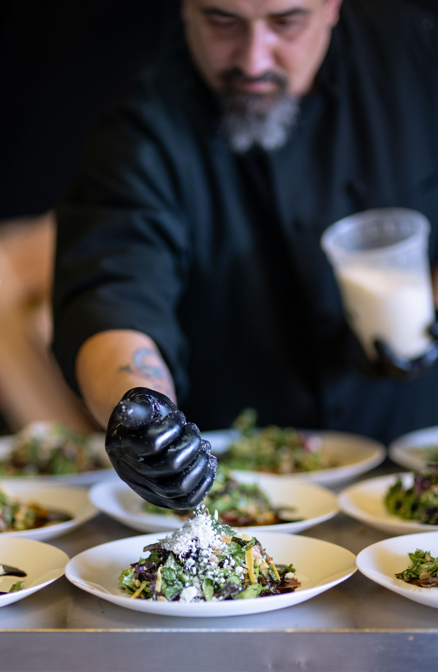 chef creating a fine dining salad sprinkling cotija on the salad