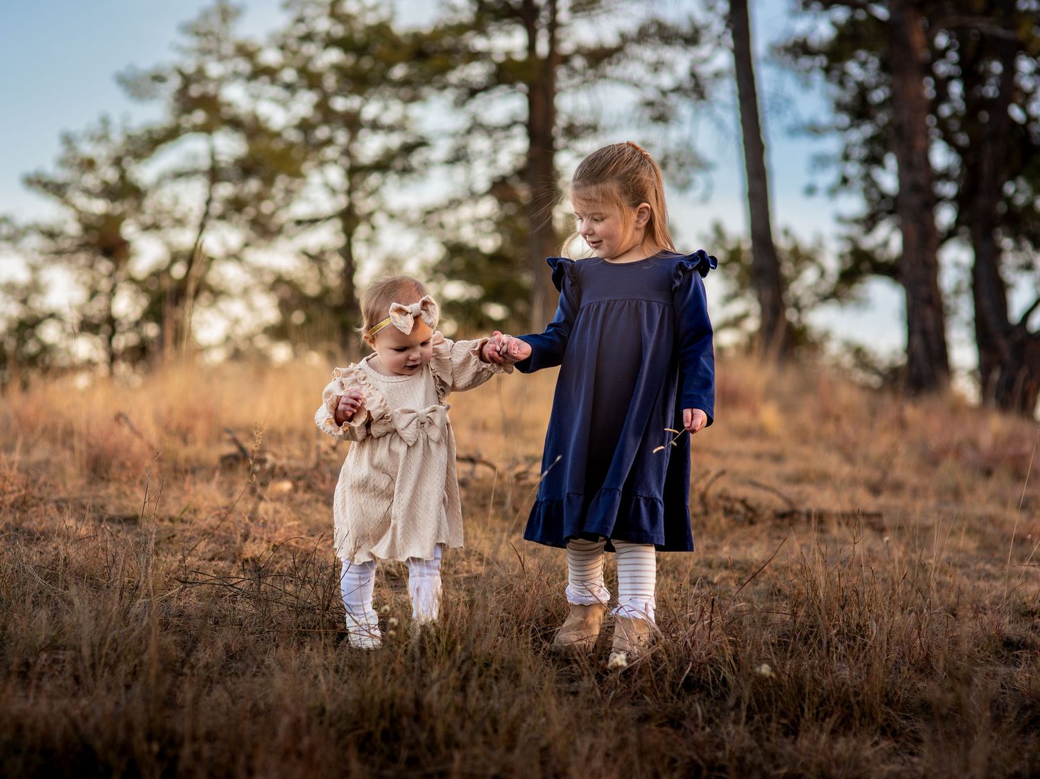 Two young sisters walking down a hill at sunset with a warm hue of light and a blue background