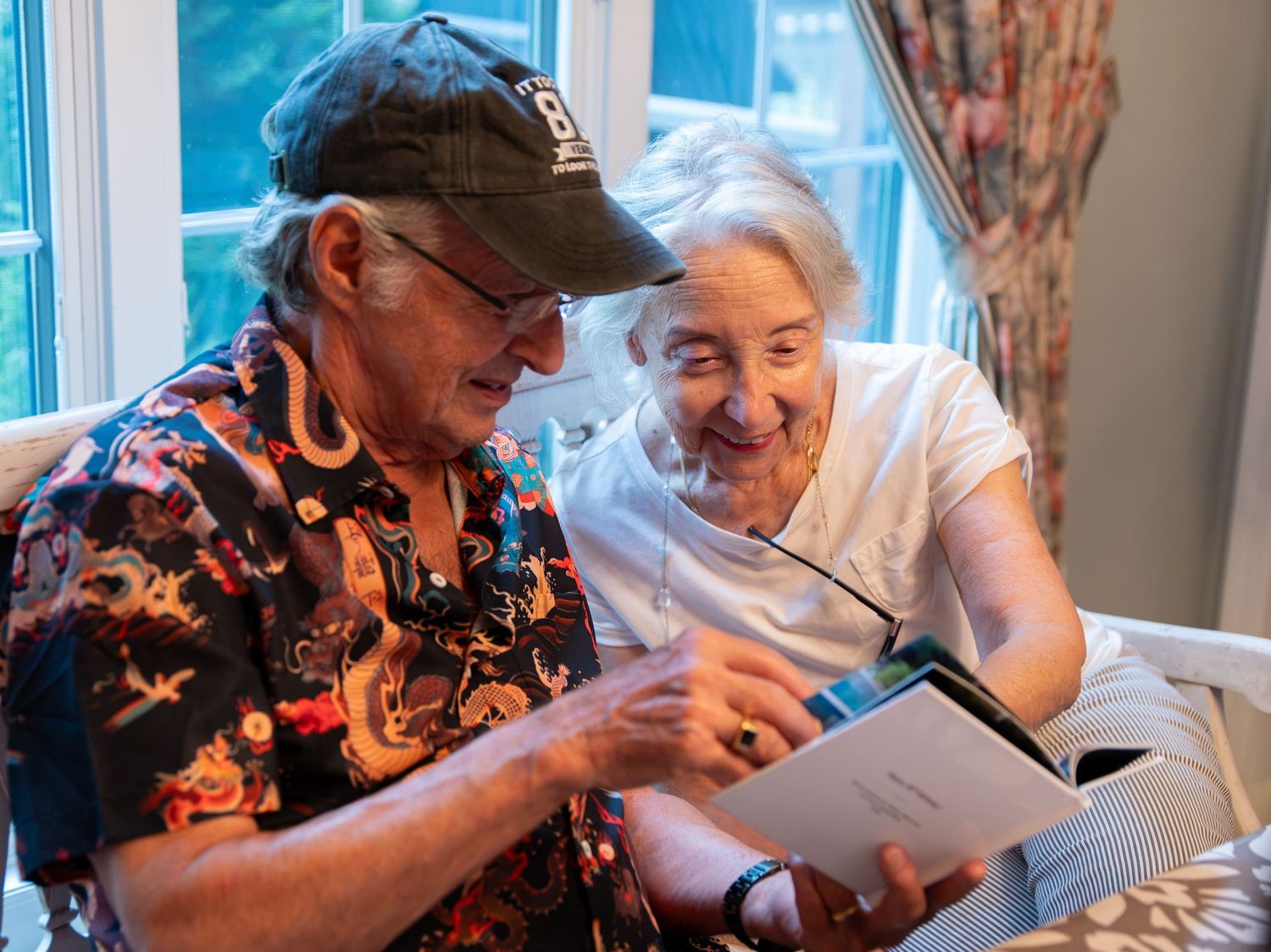 Grandfather and grandmother looking at a photo book together. Photo by Elijah Grace Photo.