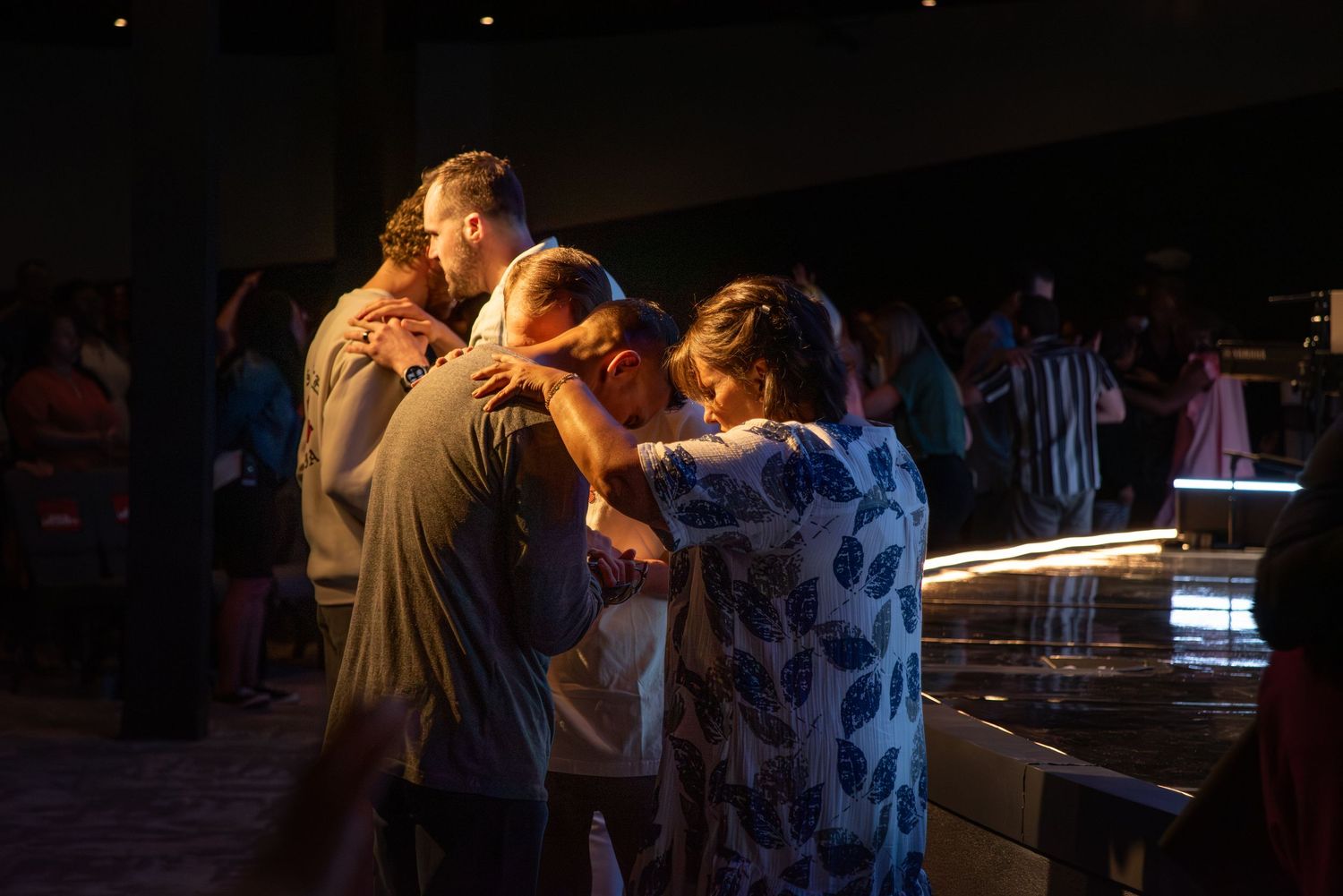 individuals praying together under warm light at Zeal Church, Colorado Springs. Photo by Elijah Grace Photo