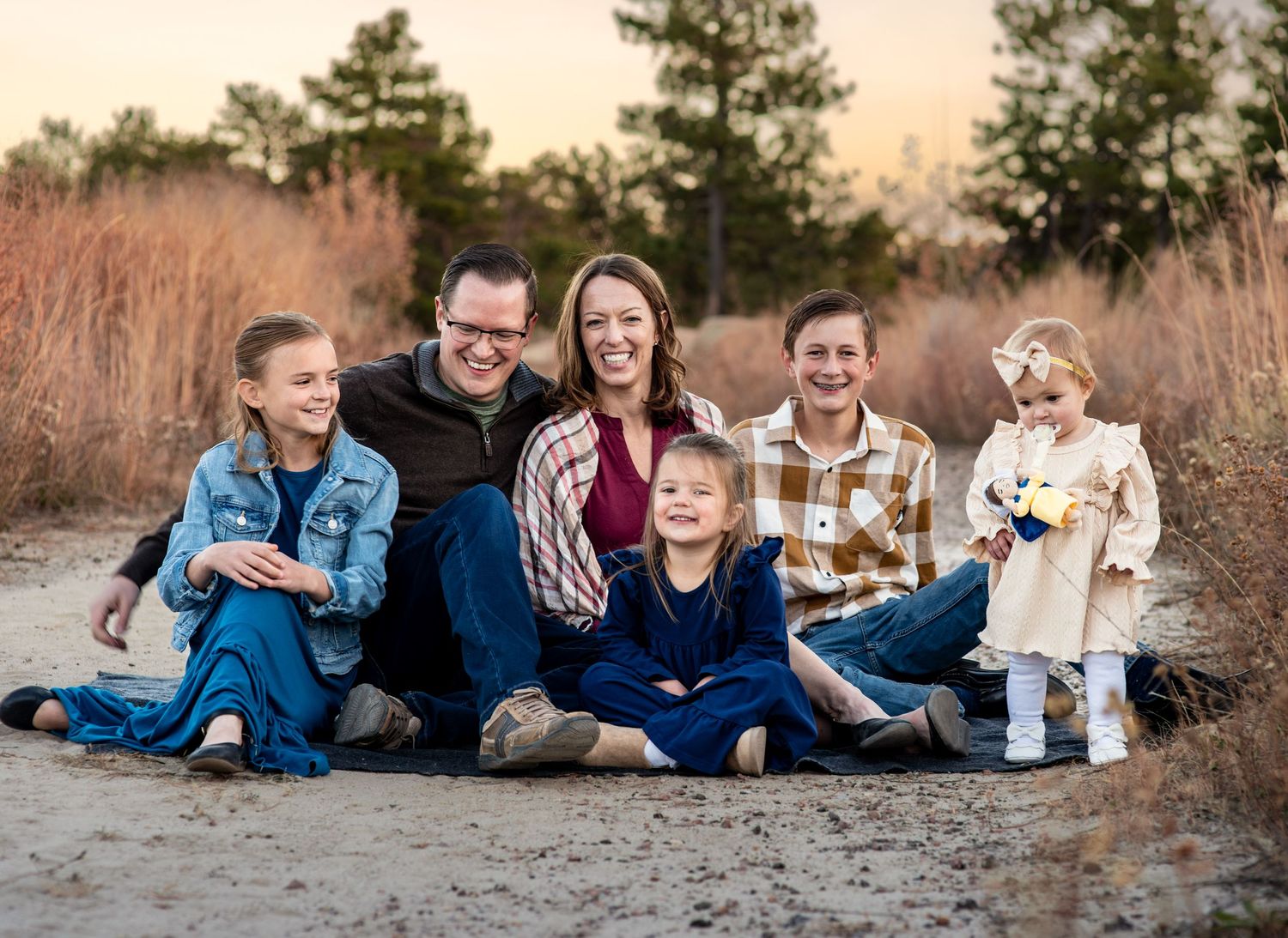 family sitting on the ground at golden hour at Ute Valley, Colorado Springs for a family portrait