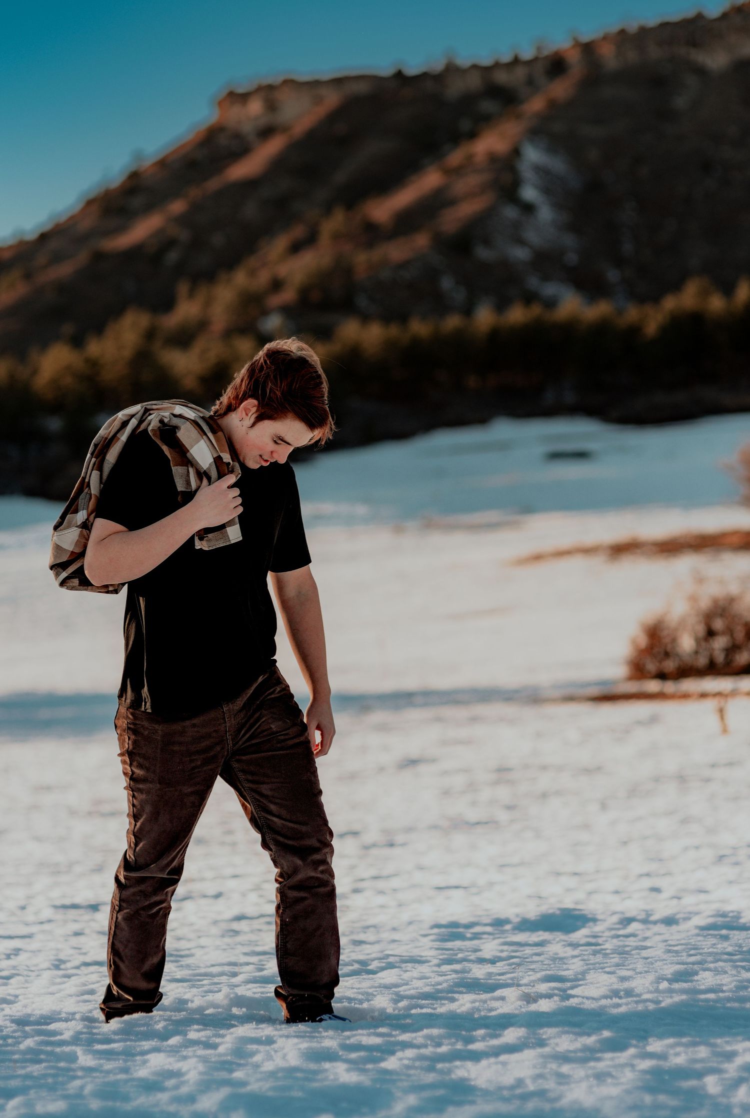 senior photo of a young man walking through the snow