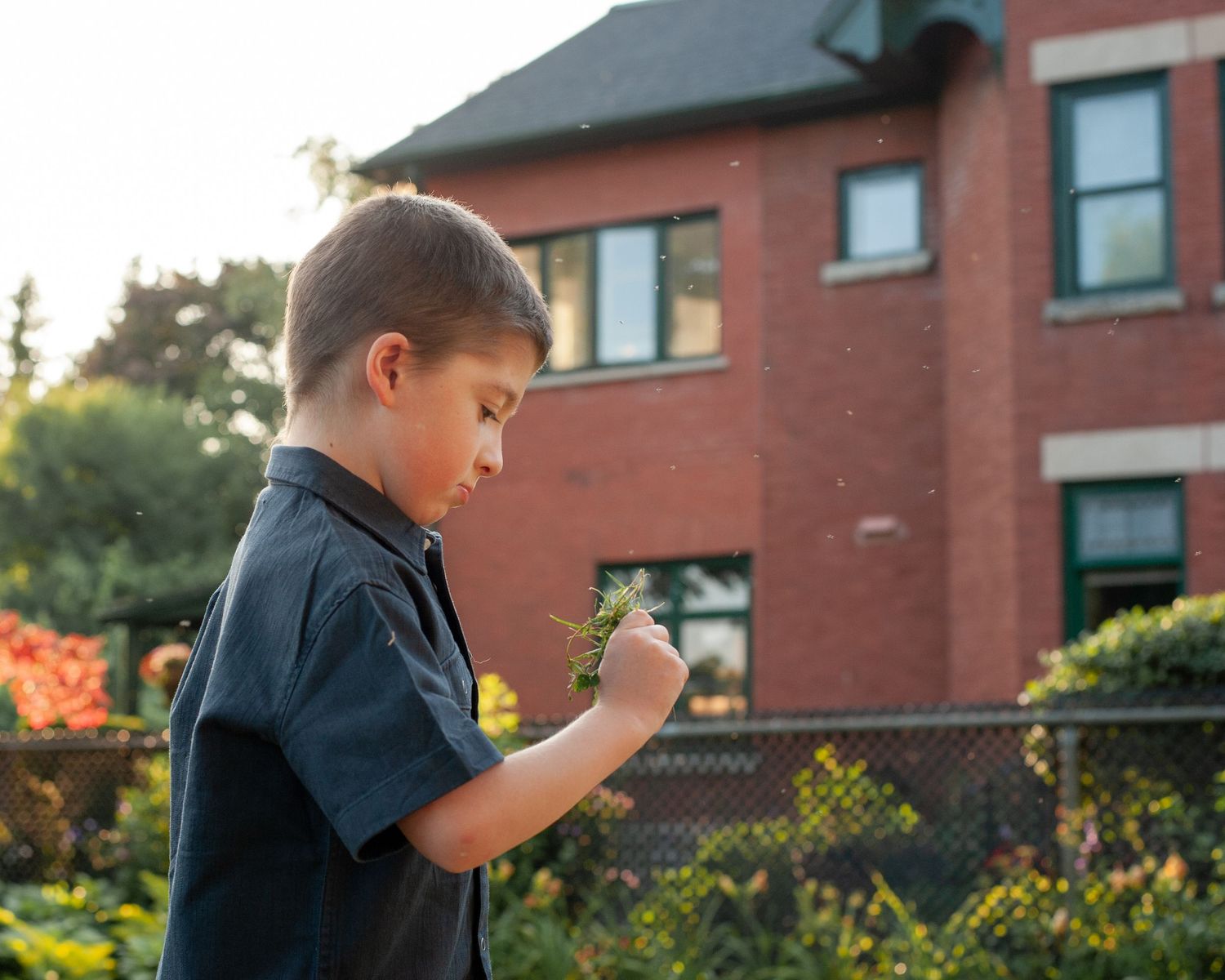 Child in navy blue shirt explores with curiosity in front of brick building during golden hour.