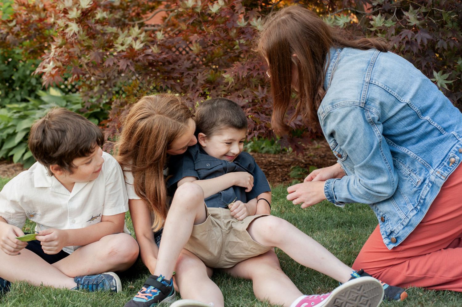Playful group sitting on grass in a garden enjoying a lighthearted moment together.