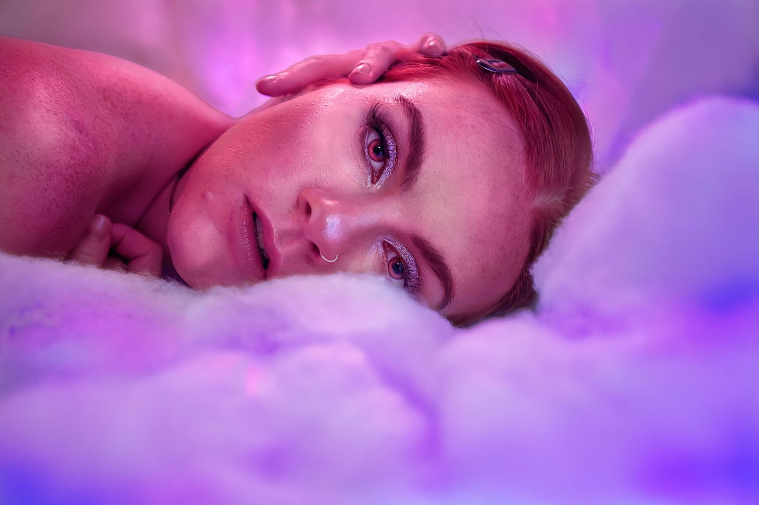 Portrait in dreamy purple and pink lighting with soft focus effects.