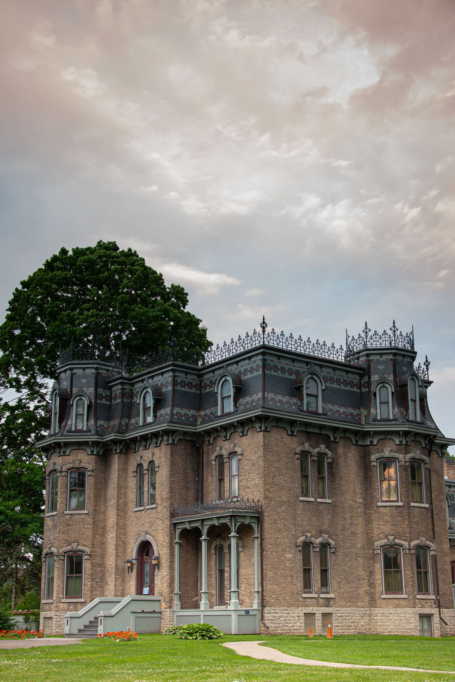 Gothic Revival style mansion with decorative spires and tan brick exterior under dramatic sky.