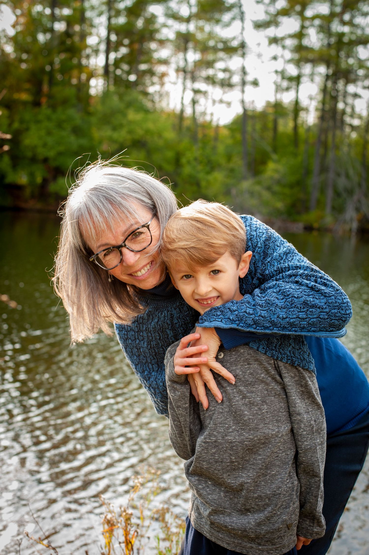 Heartwarming moment shared by lake with trees in background.