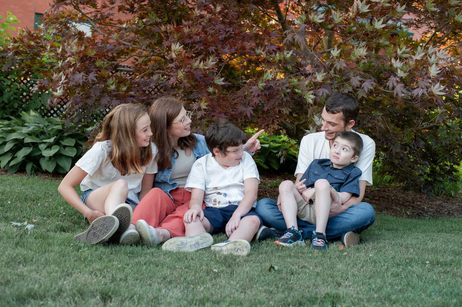 Family members relaxing together on green grass during an outdoor photo session.