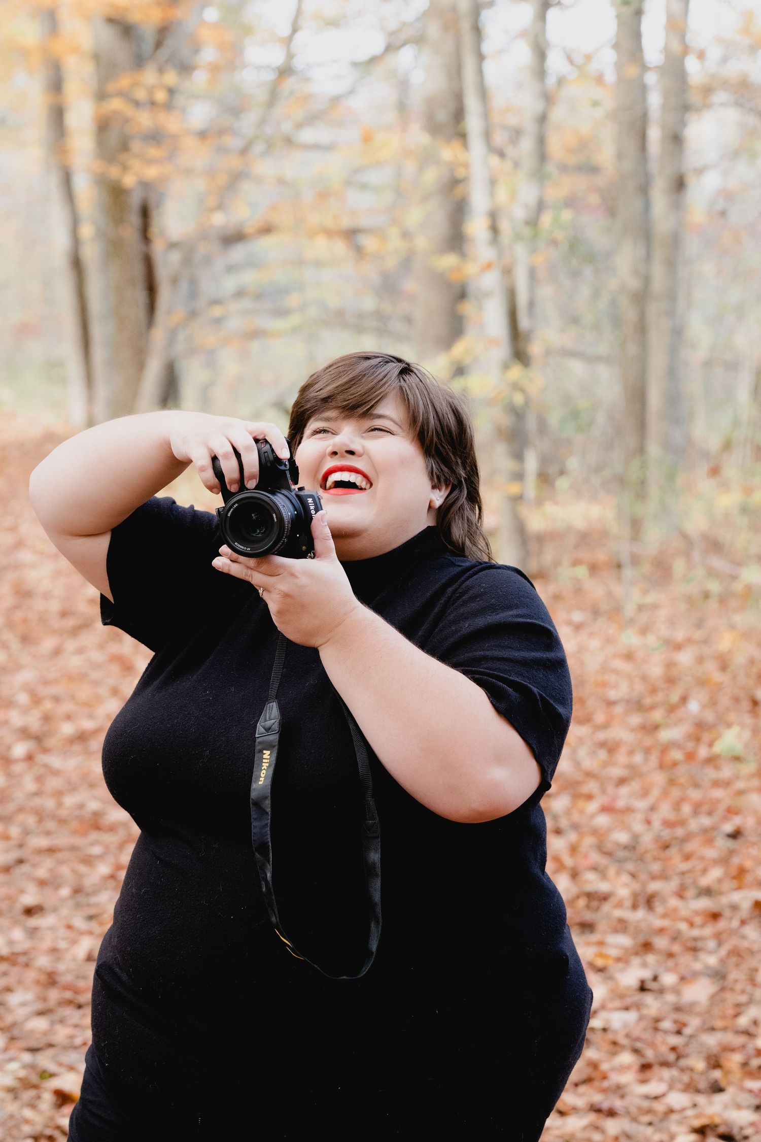Three sequential photos show a photographer in a black shirt laughing while taking pictures in a fall forest setting.