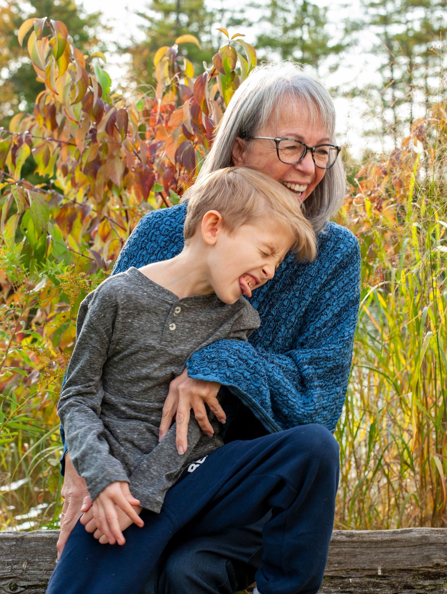 A joyful moment shared between grandmother and child surrounded by autumn foliage.