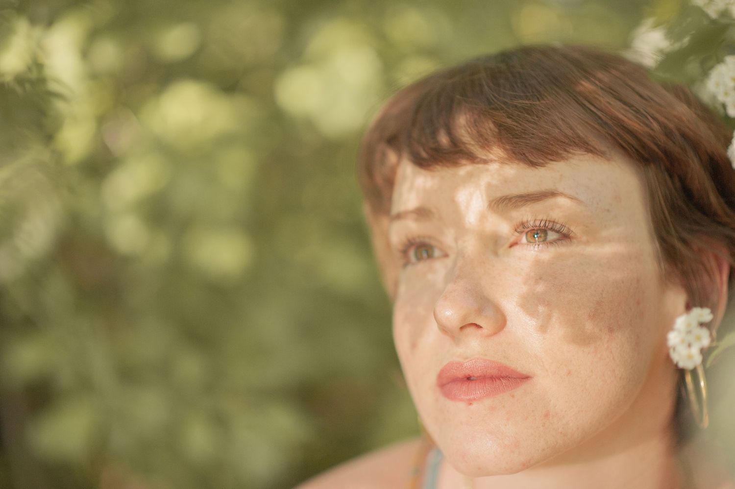 A dreamy golden-lit portrait with soft bokeh background and pearl earrings.