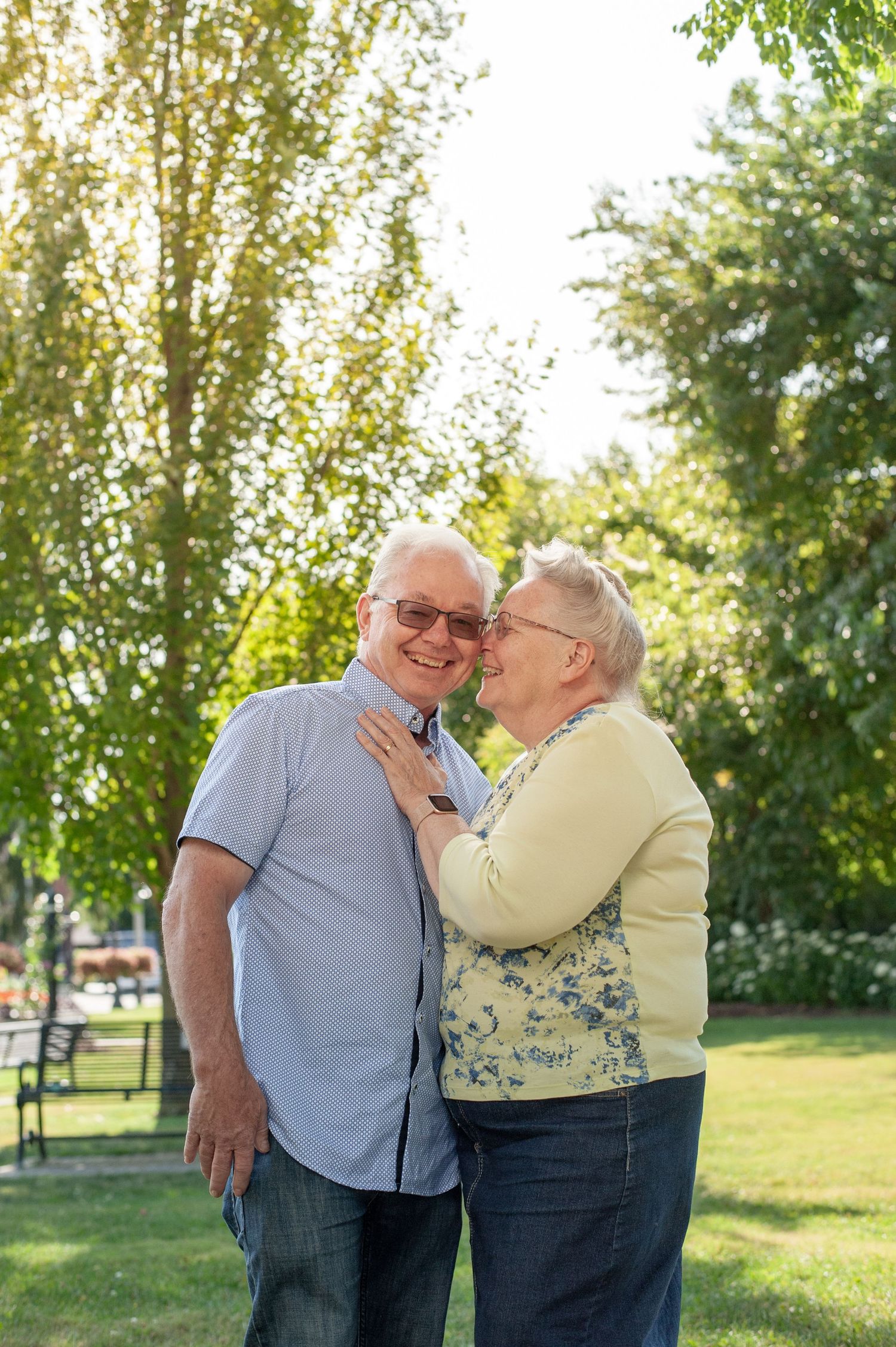 An elderly couple sharing affectionate moments outdoors in a park setting during golden hour.
