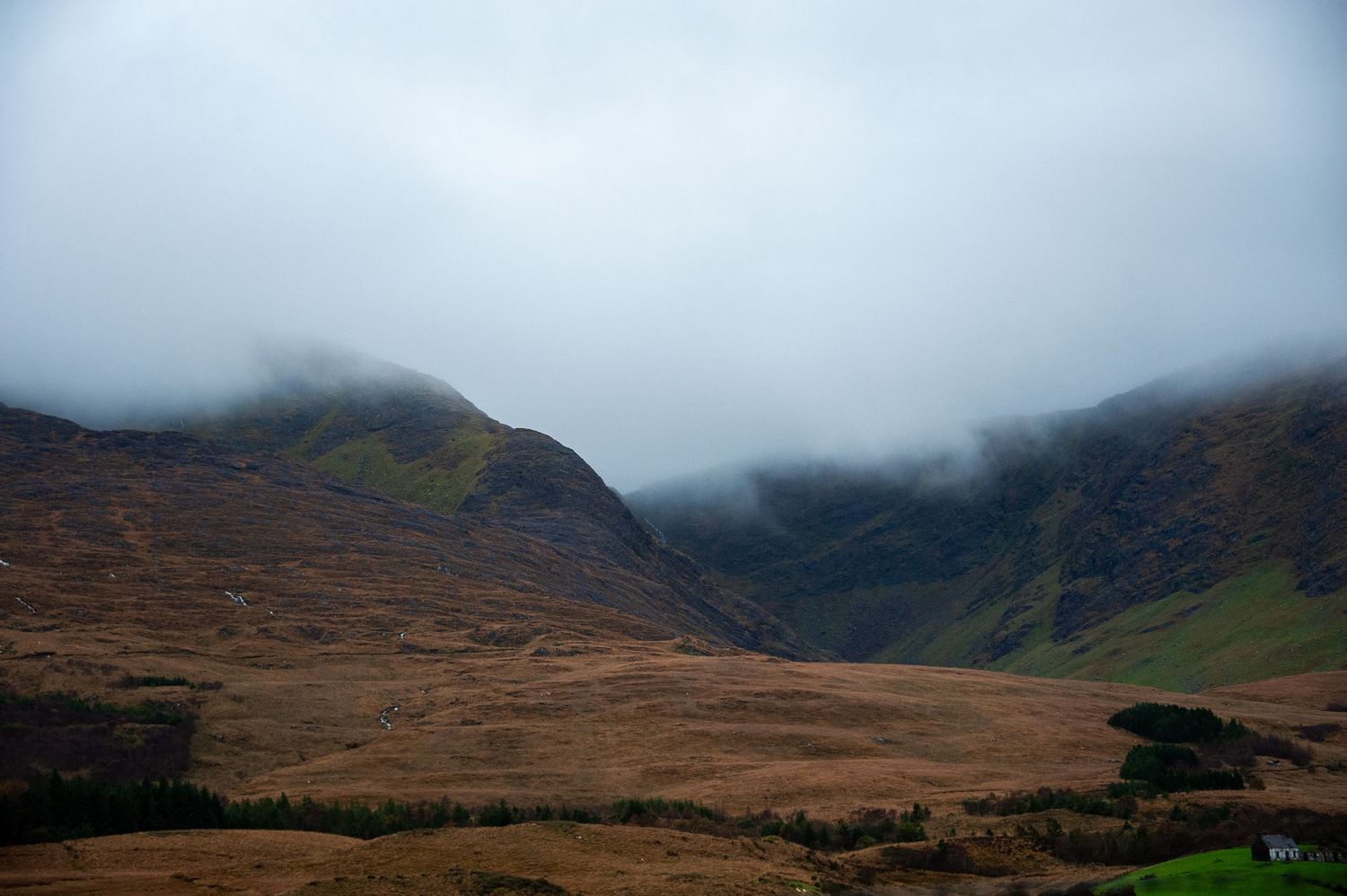 Misty mountains and brown heather moorland create a dramatic highland landscape.
