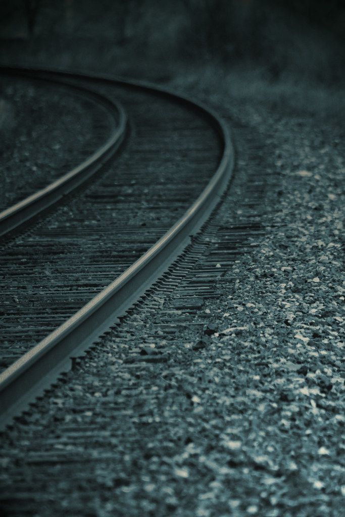Close-up view of curving railway tracks with gravel and stones along the rails.