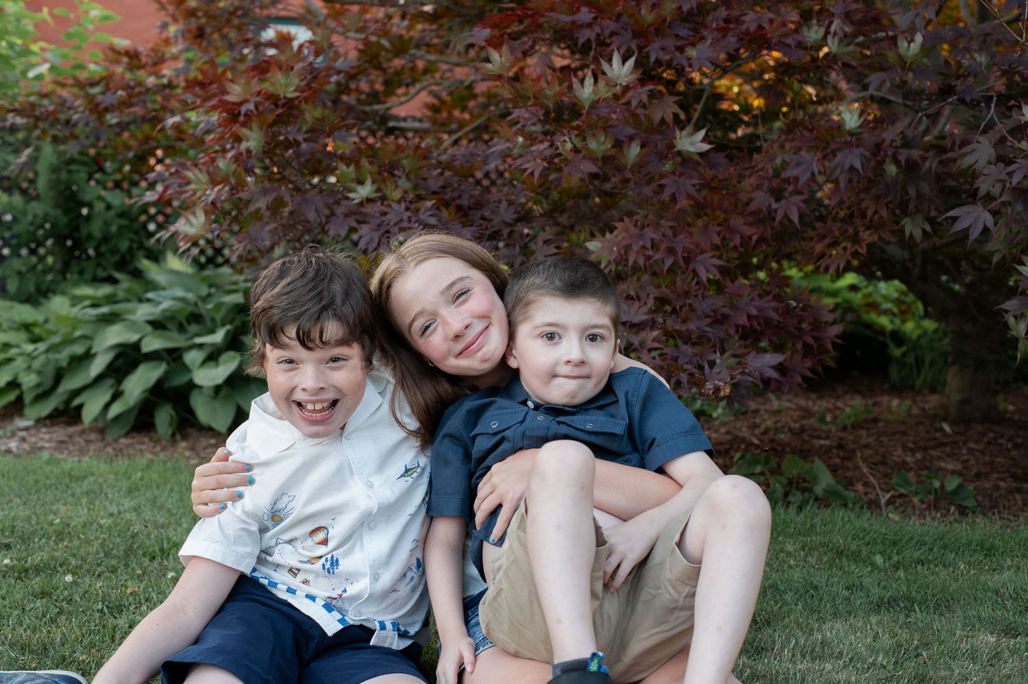 People sharing joyful moments while sitting on grass near purple flowers in a garden setting.