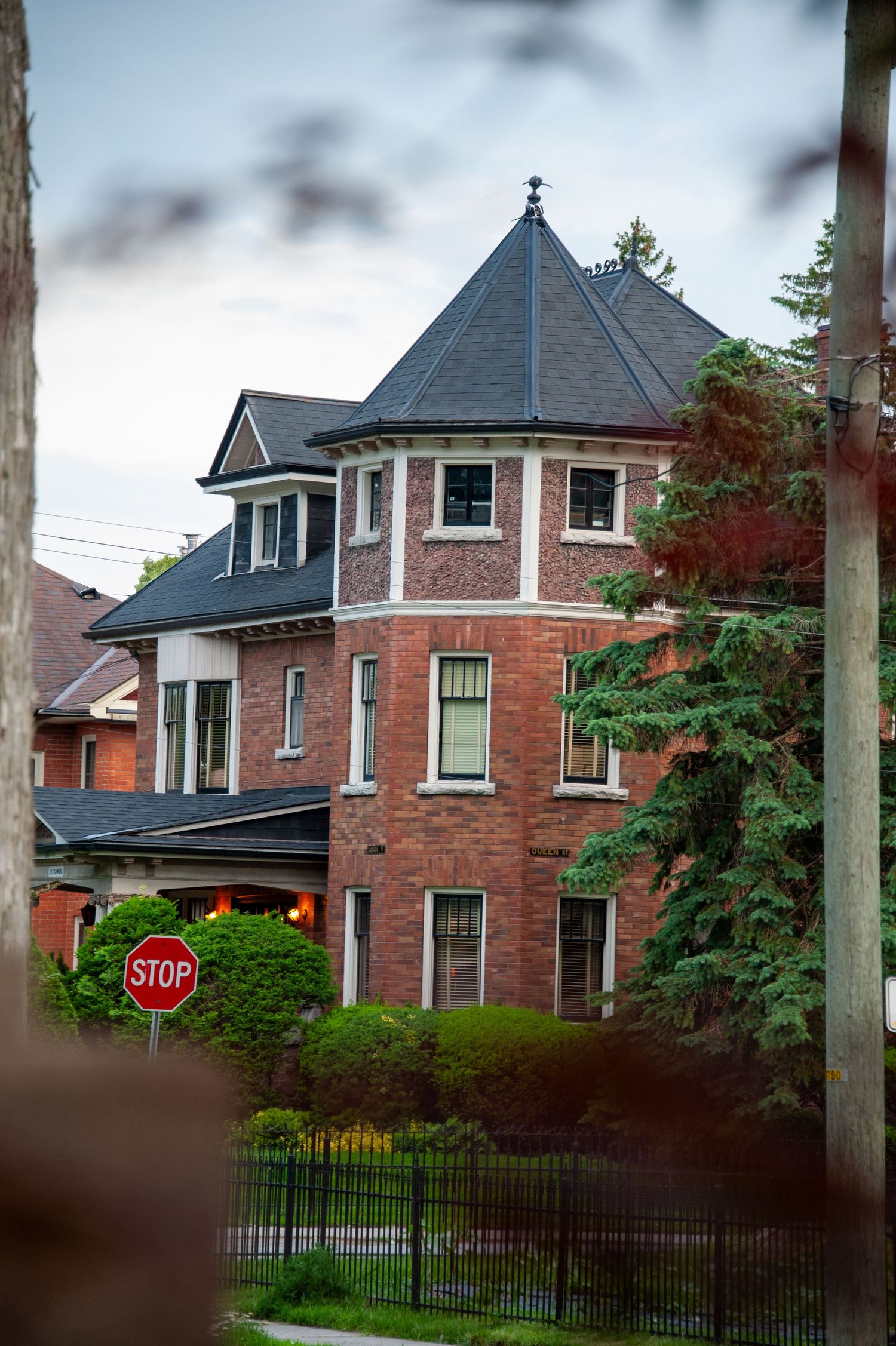 Row of Victorian brick mansions with turrets and ornate architectural details on a tree-lined residential street.