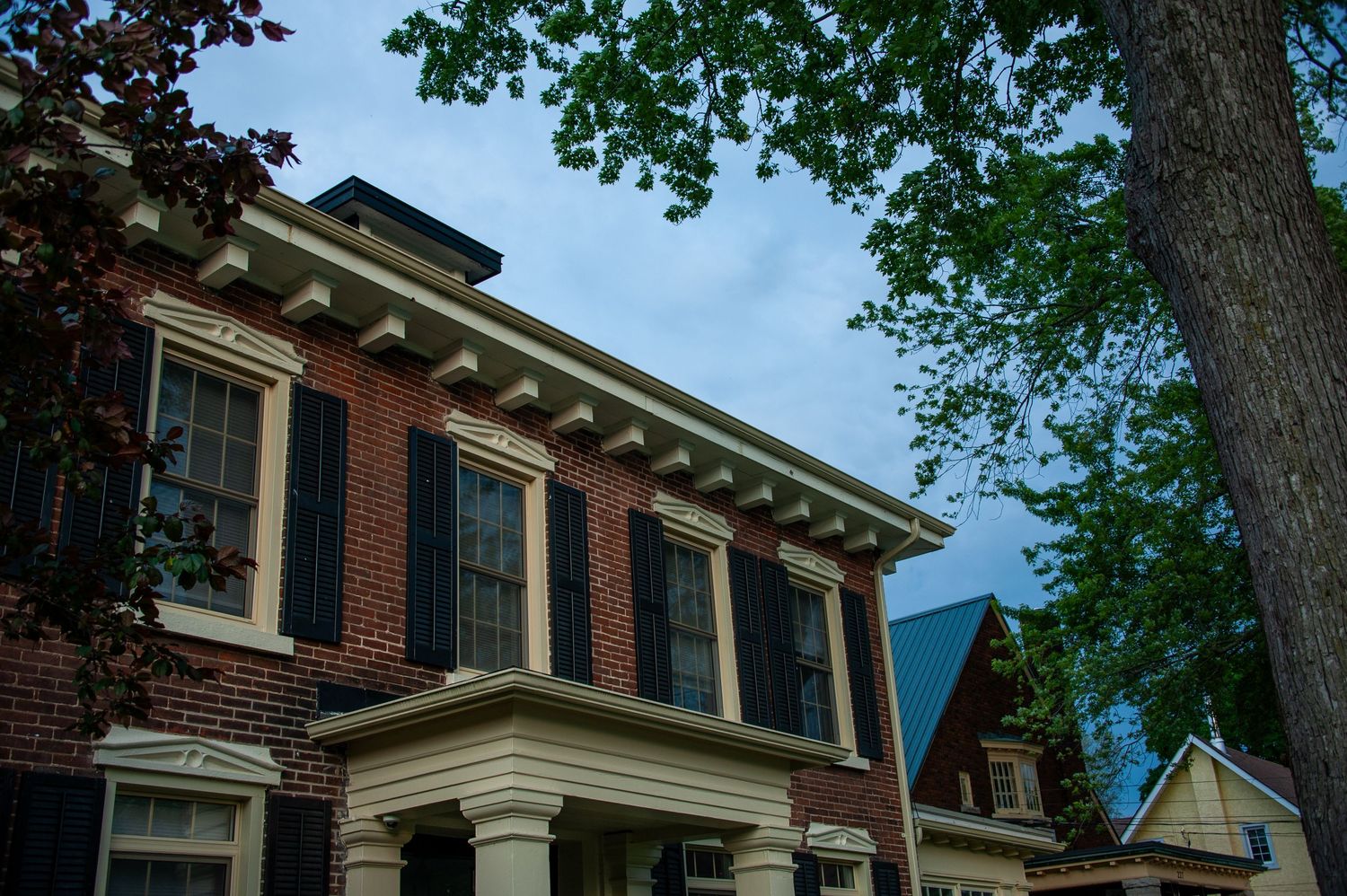 Historic brick building with classical columns and overhanging cornice detail.