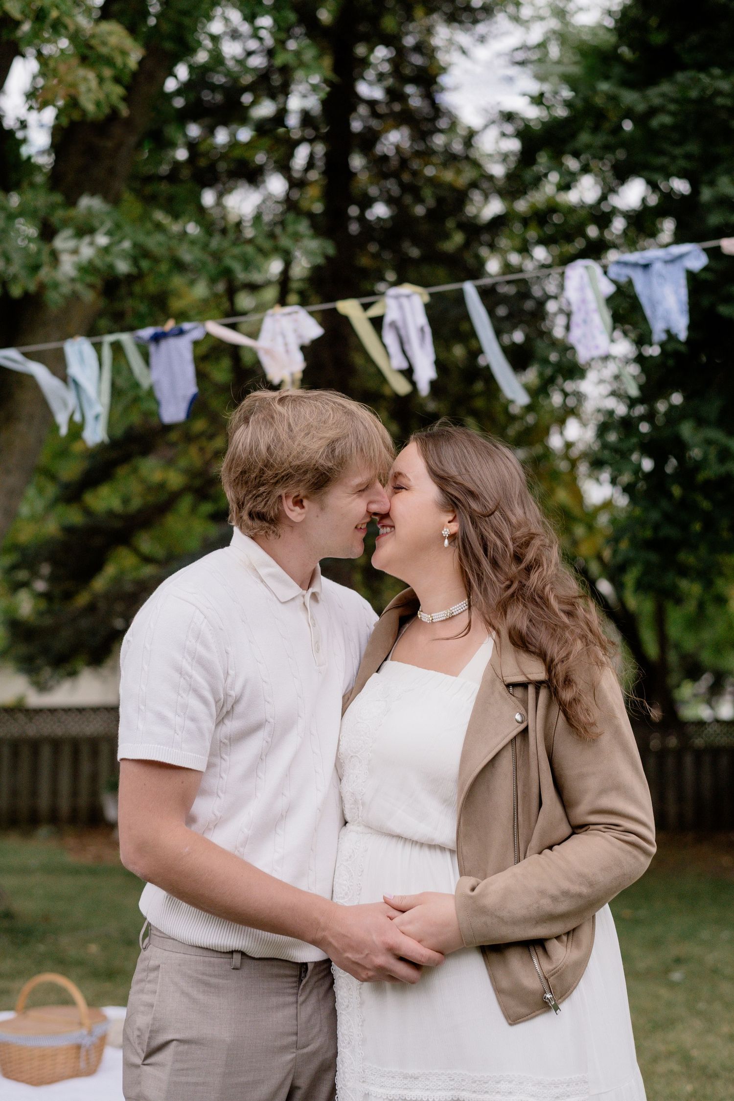 A couple shares tender moments outdoors with white laundry hanging on a clothesline in the background.