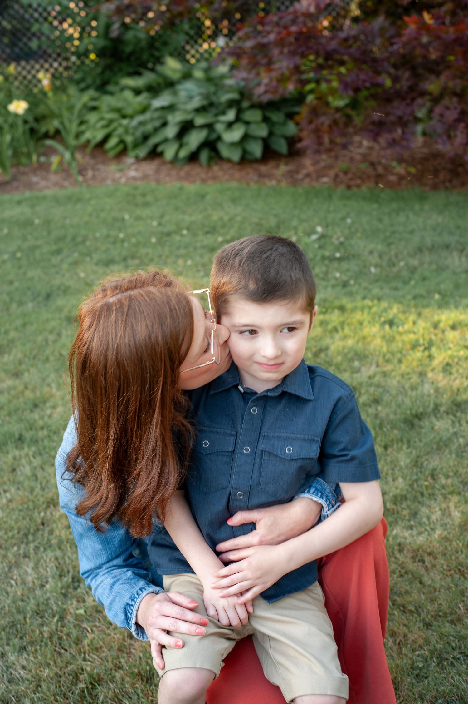 Tender family moments shared on a red bench in a lush garden setting.