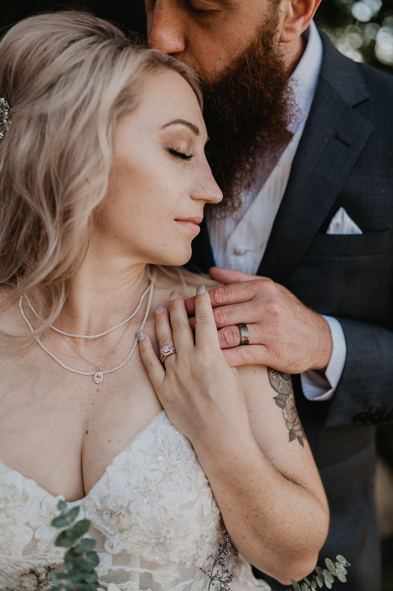 Tender moment of bride and groom with her eyes closed as he gently touches her neck.