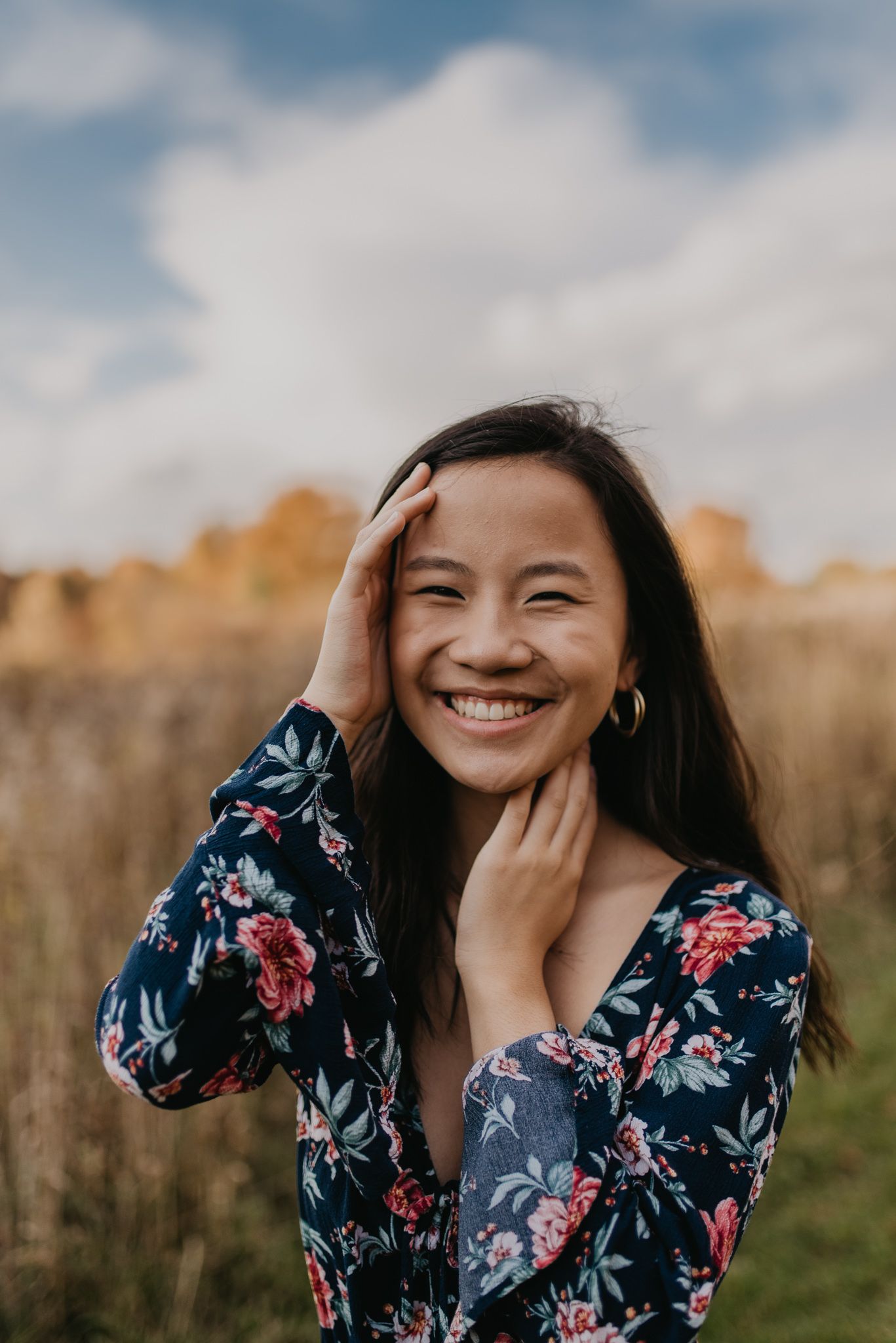 Joyful portrait in floral dress with warm autumn scenery behind.