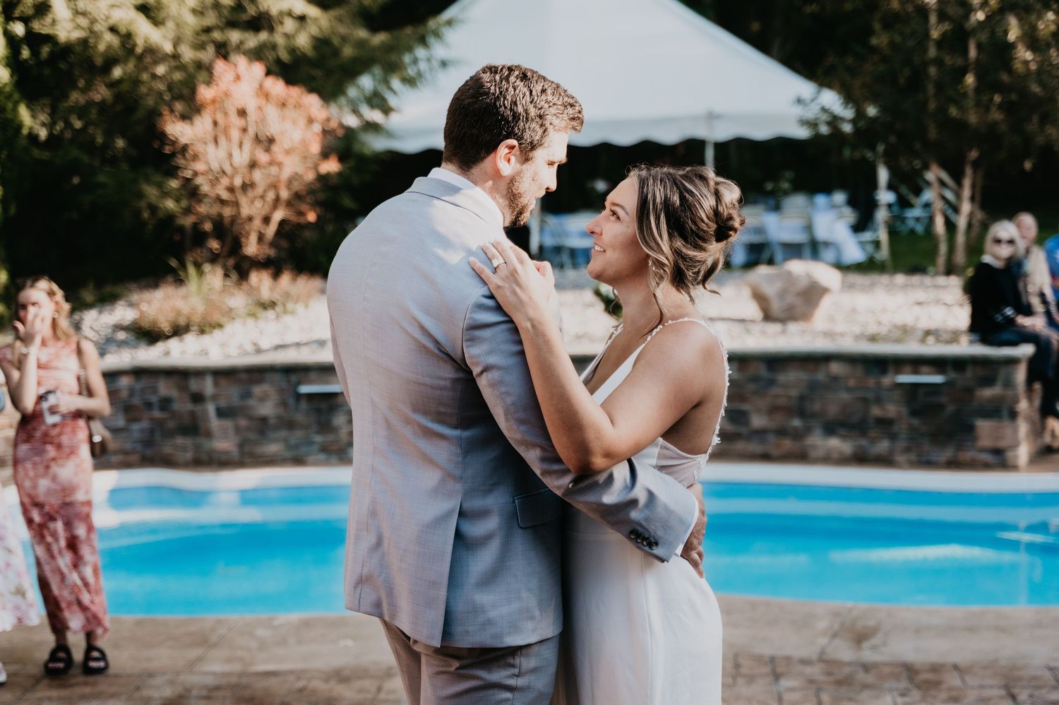 A couple shares a tender dance moment beside a swimming pool during their wedding celebration.