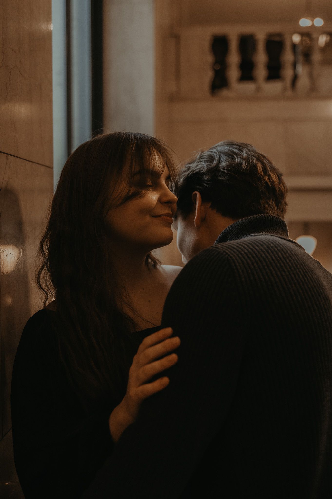 A romantic couple shares an intimate moment in a dimly lit setting with sepia toned lighting.