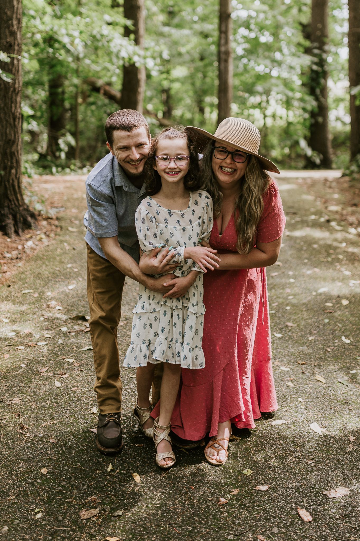 A joyful family photo taken on a wooded path during a summer day.