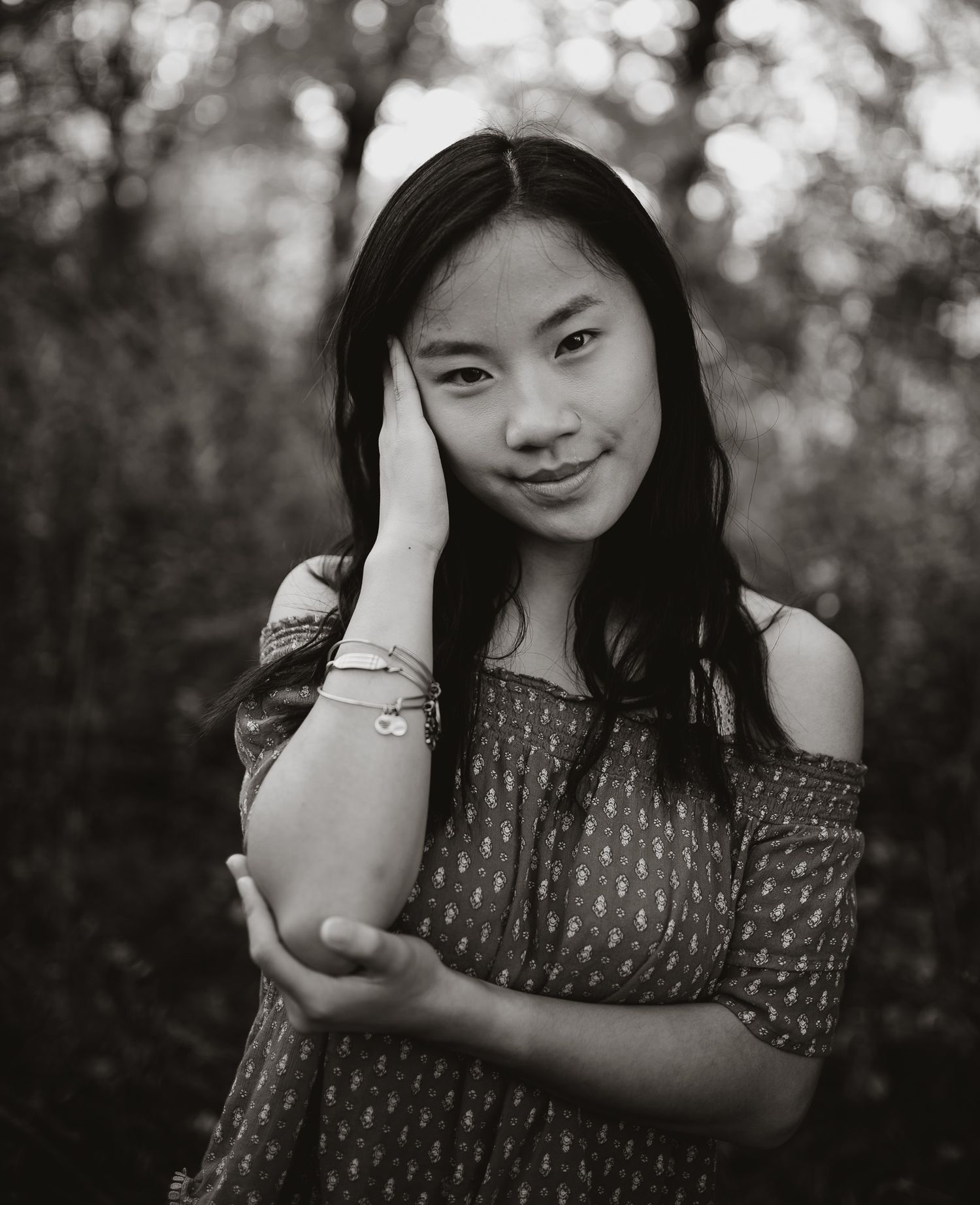 Classic black and white portrait with soft bokeh background and off-shoulder top.