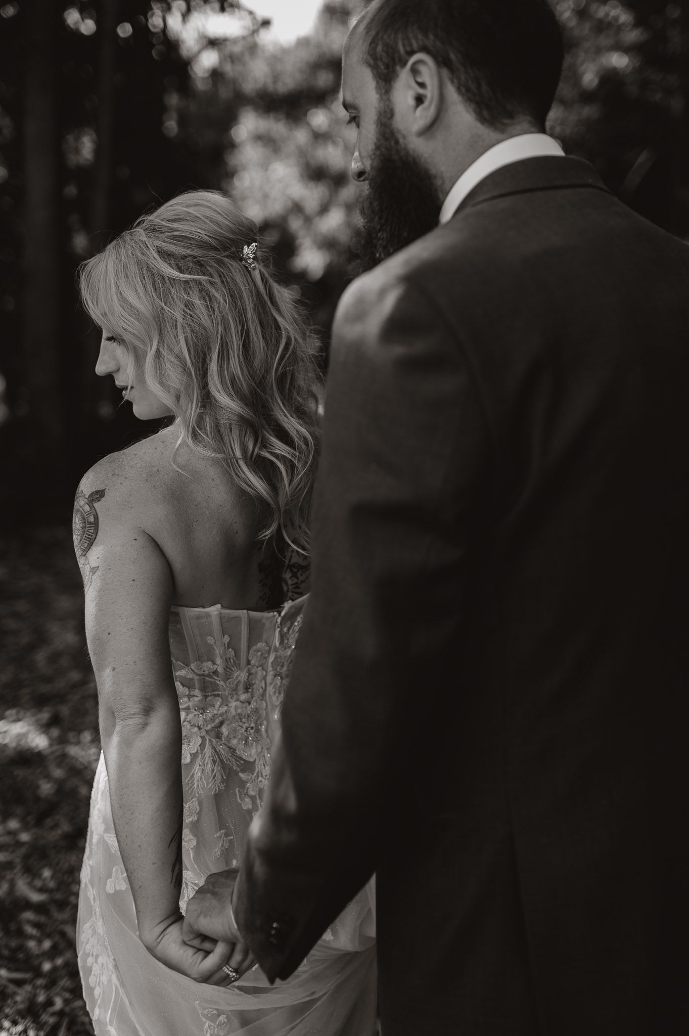 Artistic black and white portrait of bride and groom sharing an intimate moment outdoors.
