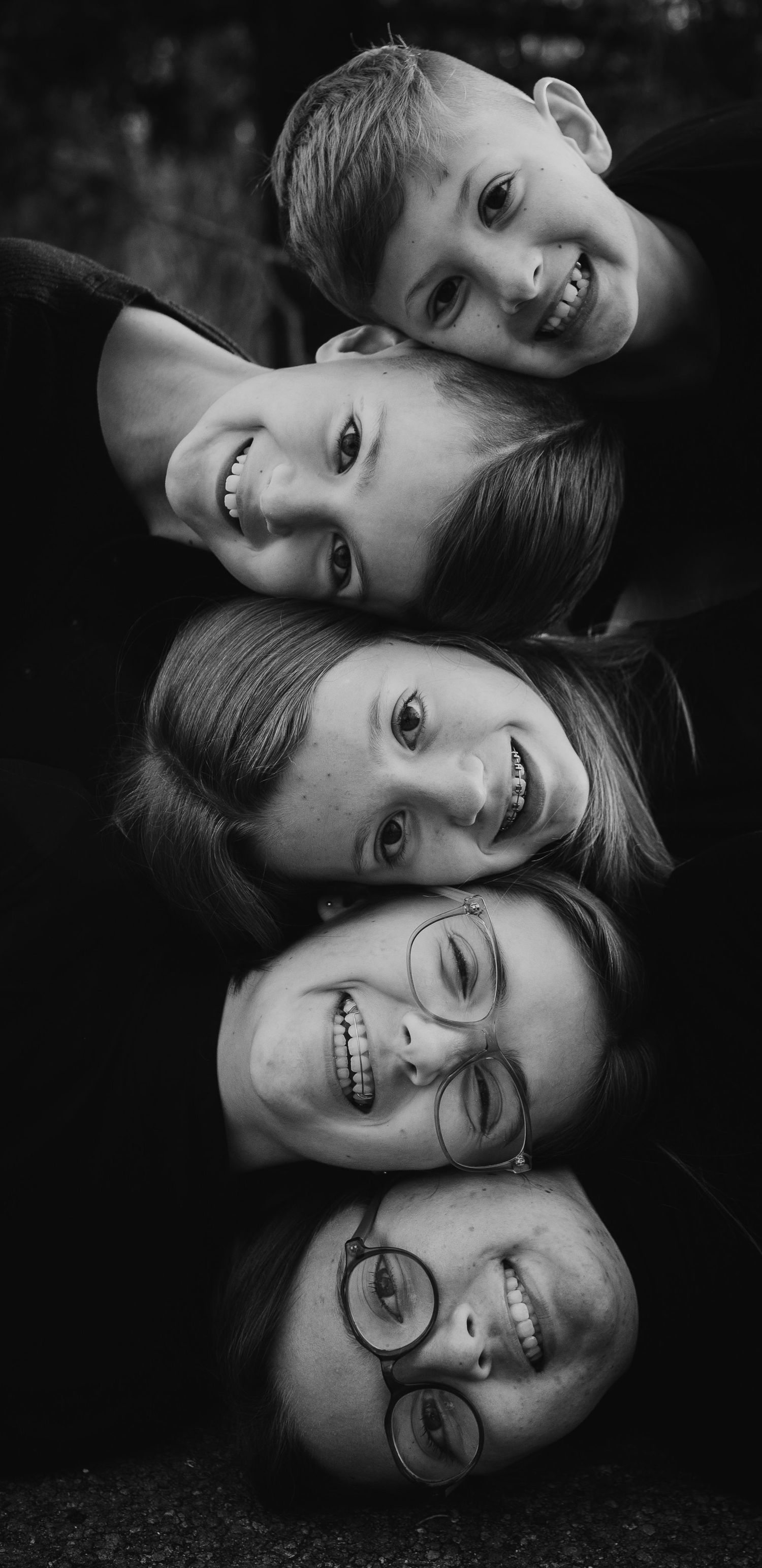 Five smiling faces stacked vertically in a playful black and white portrait.