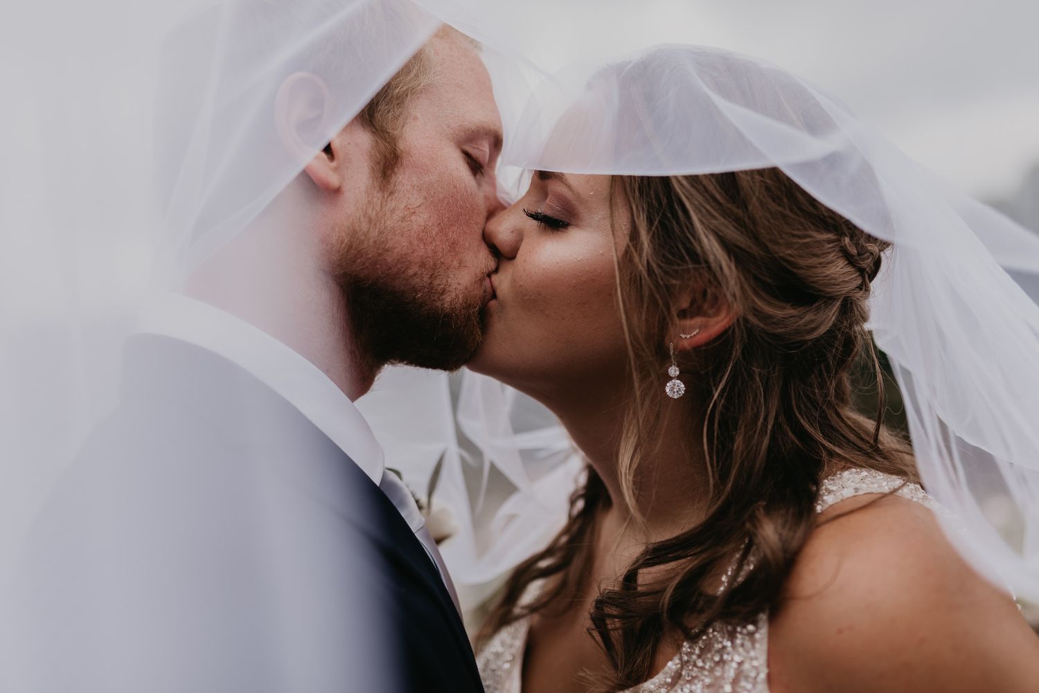 Romantic close-up shots of newlyweds embracing under a flowing white veil.