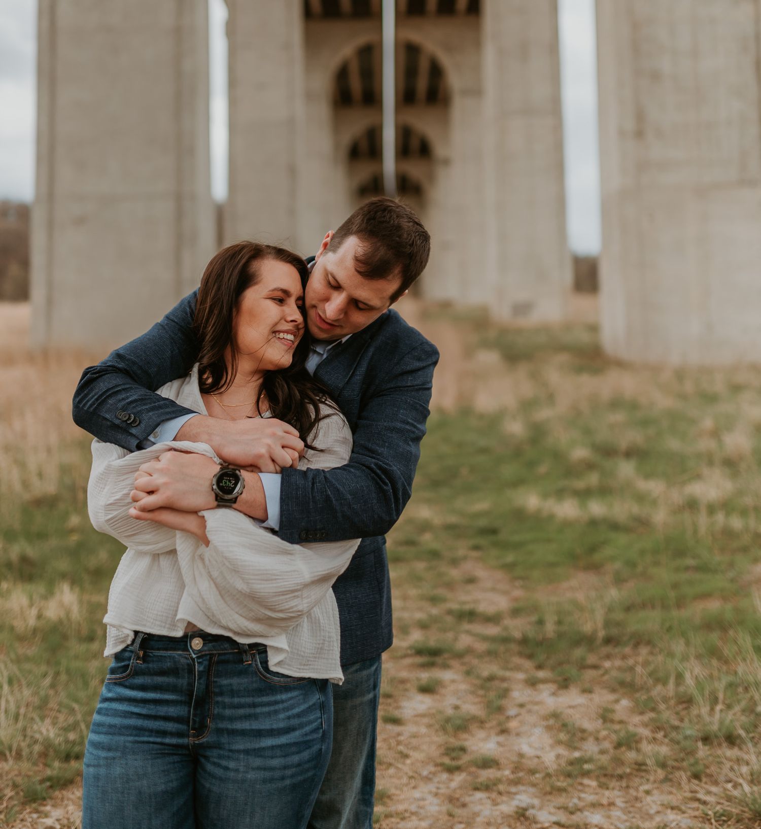 A candid moment between two people embracing under architectural columns.