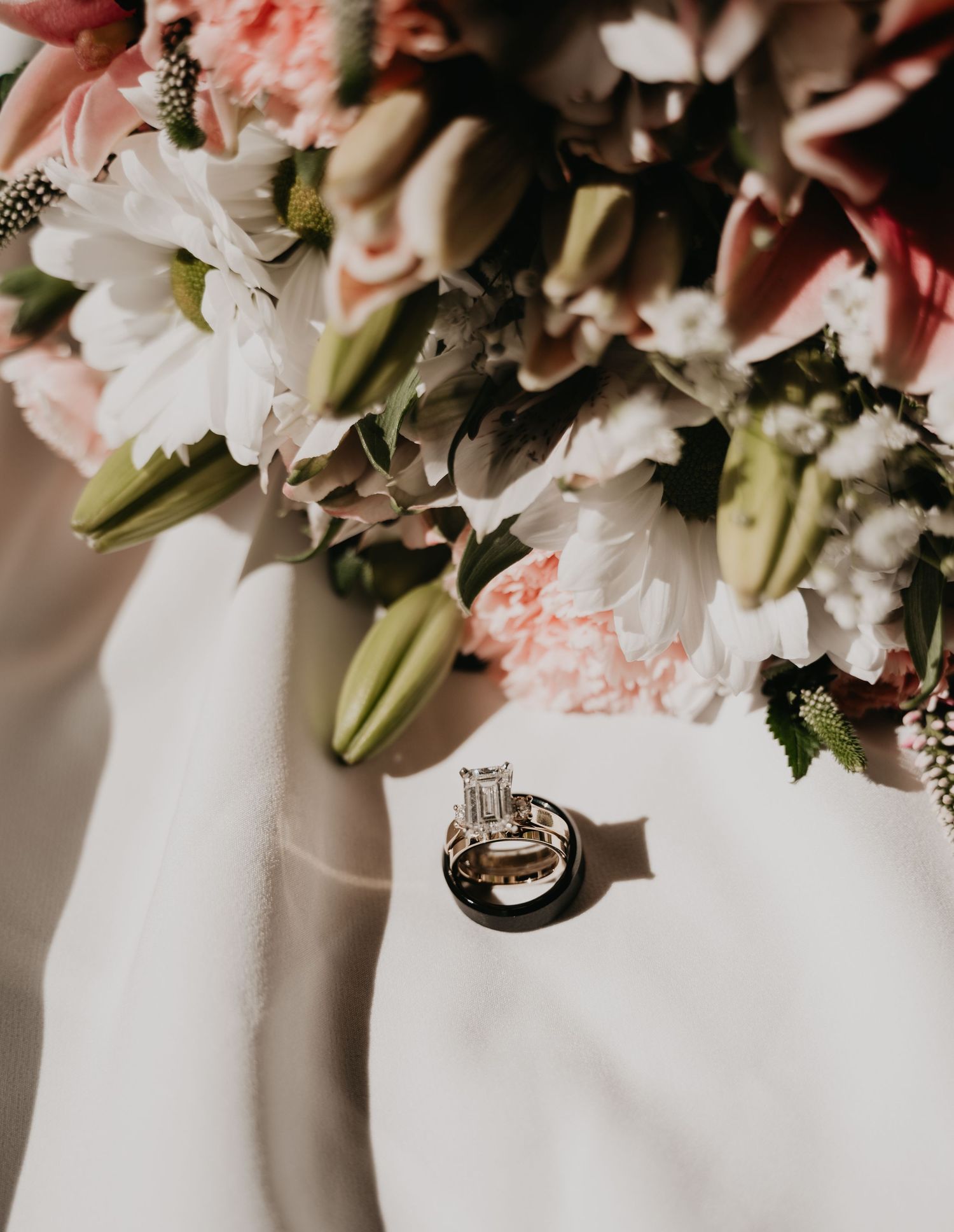 Close-up detail of pink and white wedding floral arrangements against a white tablecloth background.