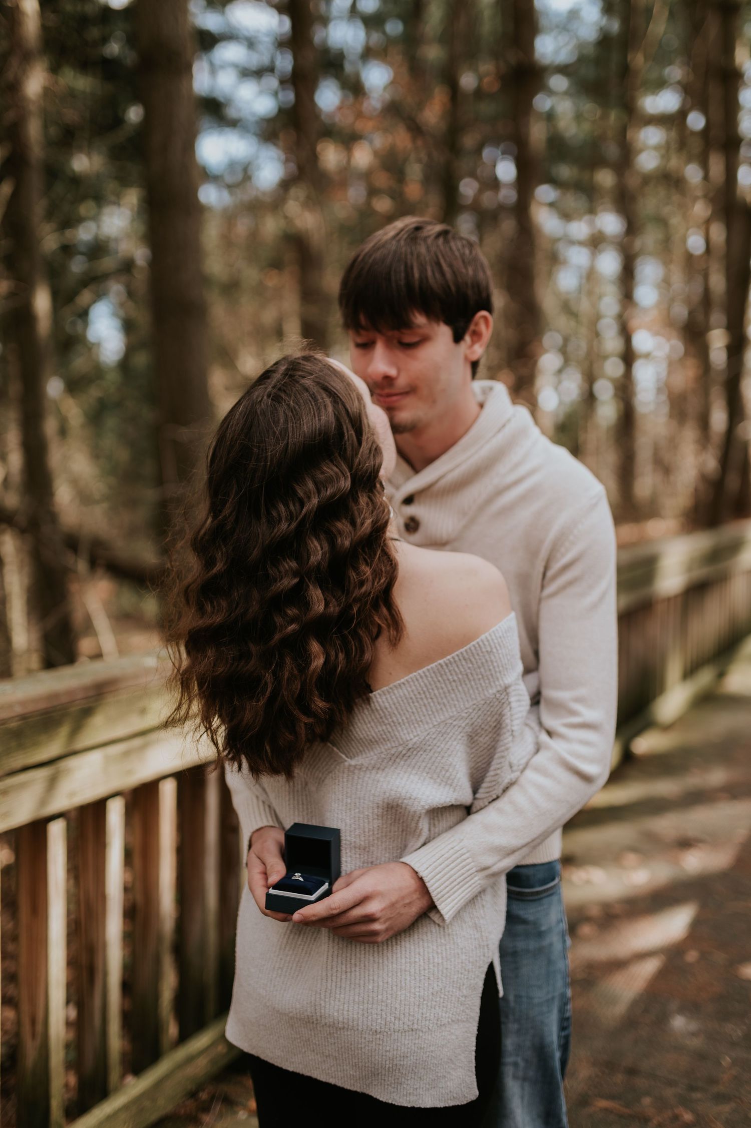A romantic moment captured on a wooden boardwalk in a forest setting.