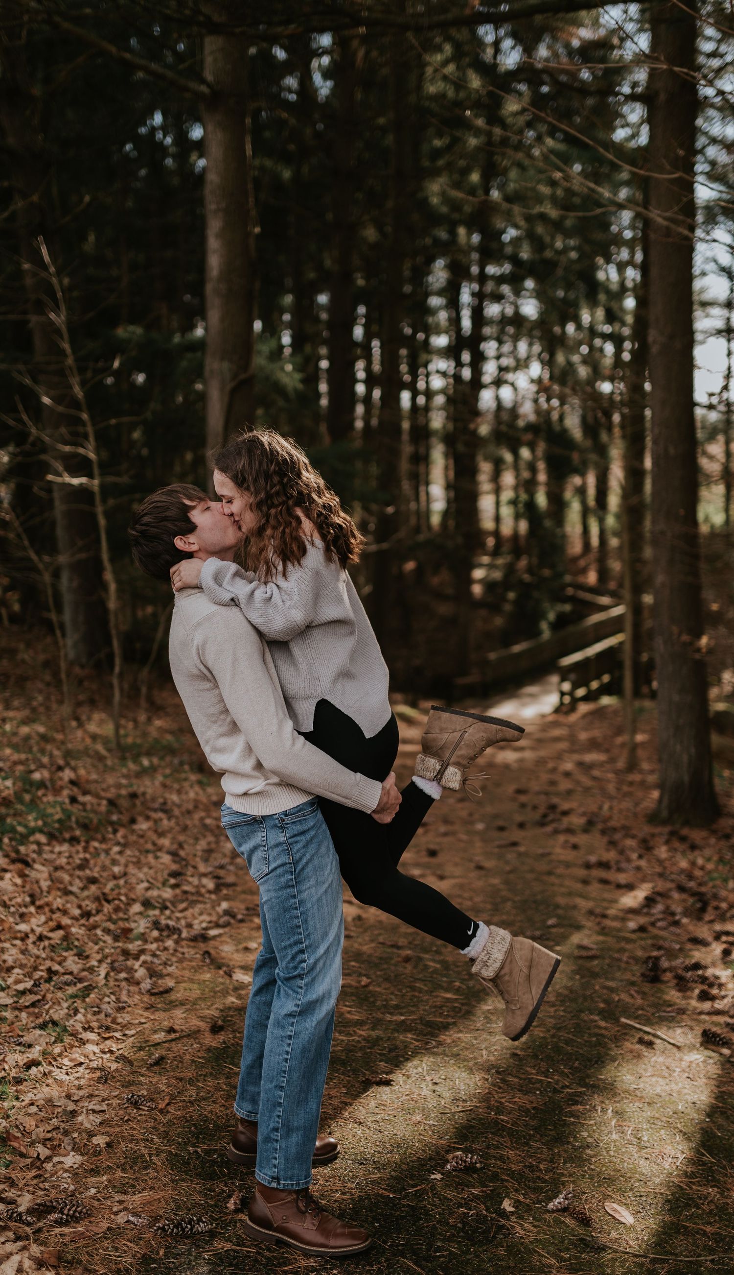 A couple embracing in a romantic moment on a wooded forest trail.